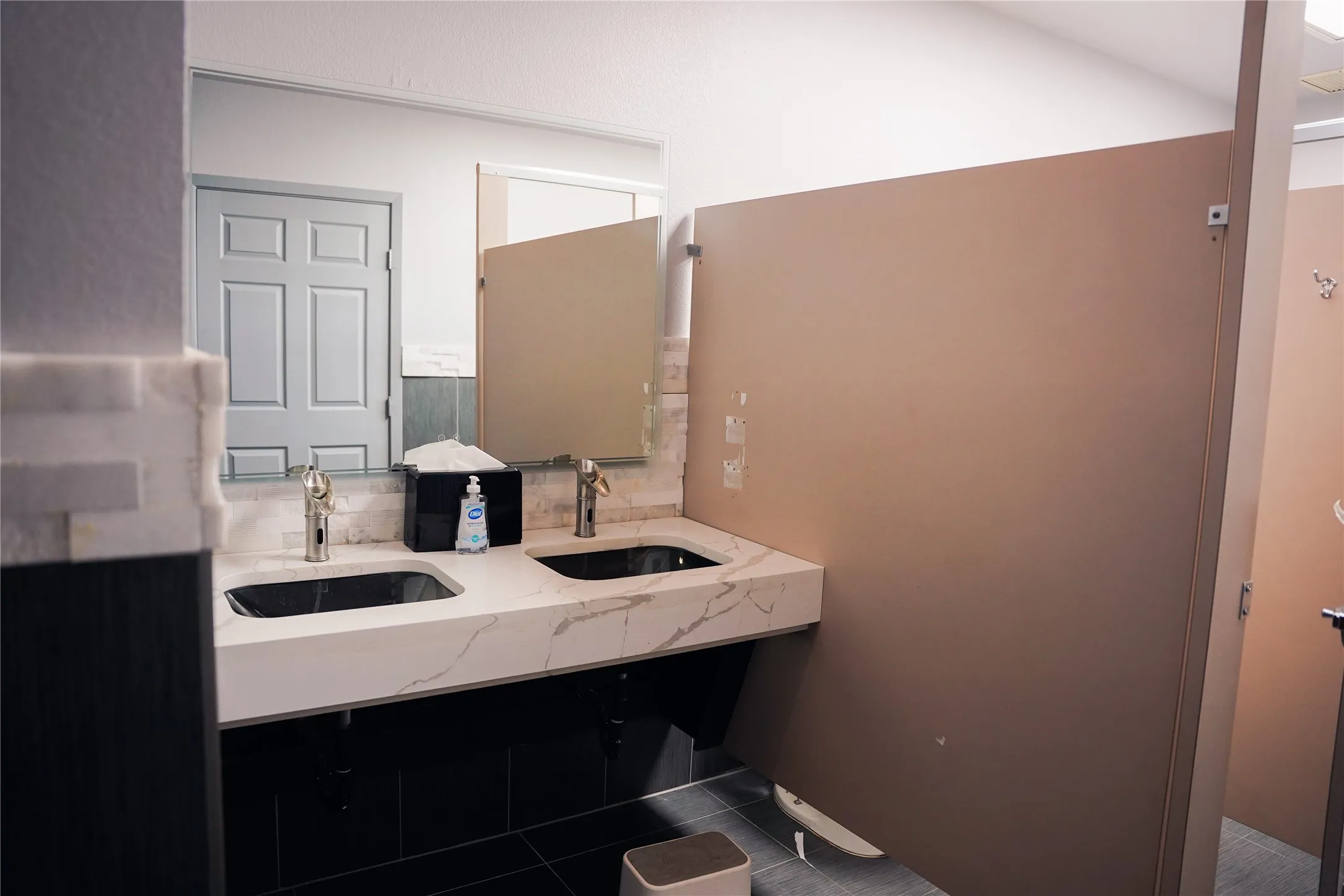 Dual black vessel sinks with gold-finish faucets set in a white marble-look countertop