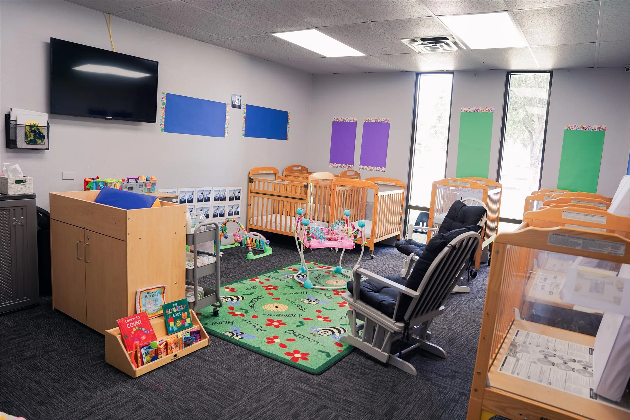 Recessed lighting, wood-finish cabinetry, mounted flat-screen display, large windows, and carpeted flooring
