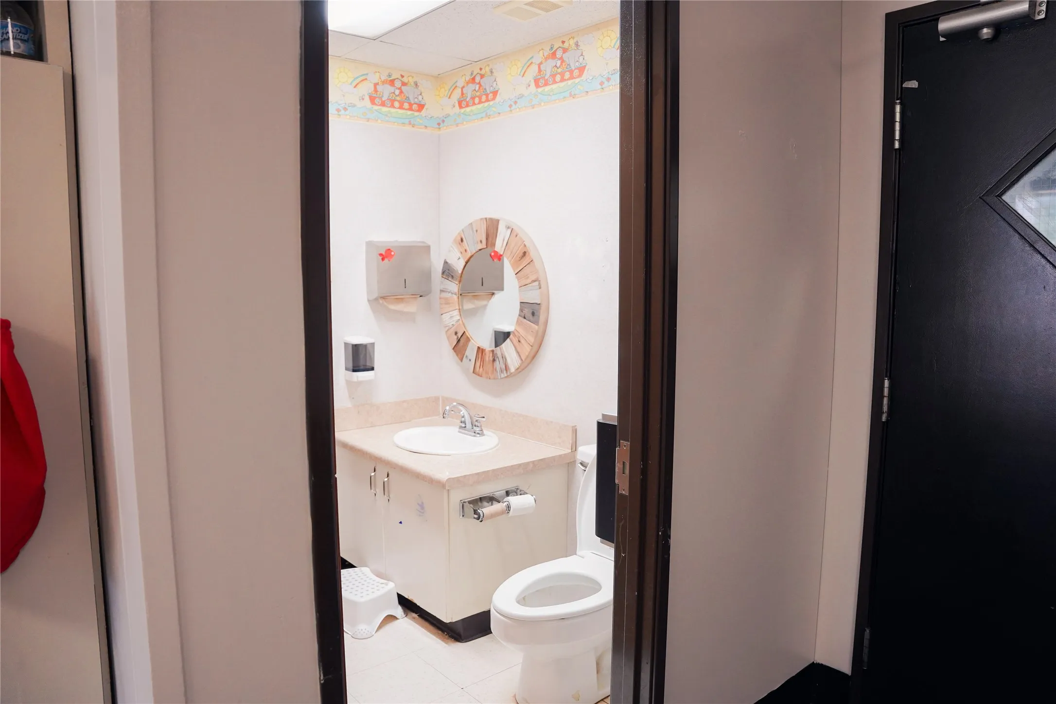 White vanity with an integrated sink and light-toned countertop, complemented by a round mirror with a wood-finish frame