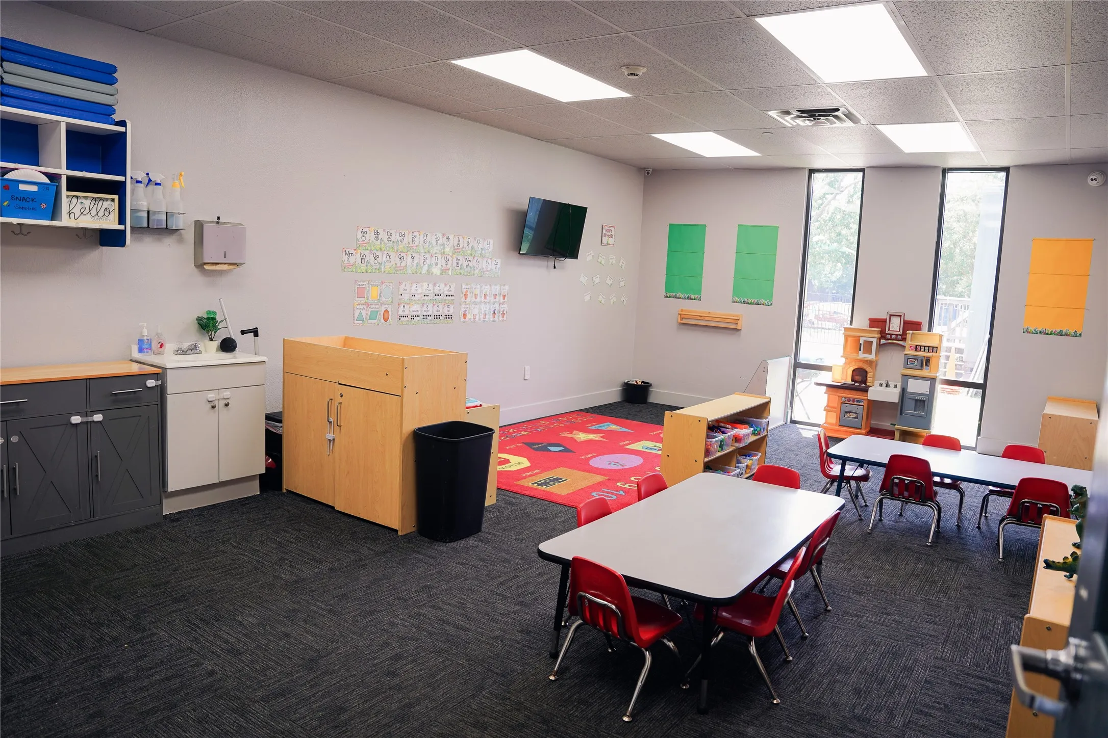 Recessed lighting, wood-finish cabinetry, built-in wall shelving, sink with countertop, and large windows