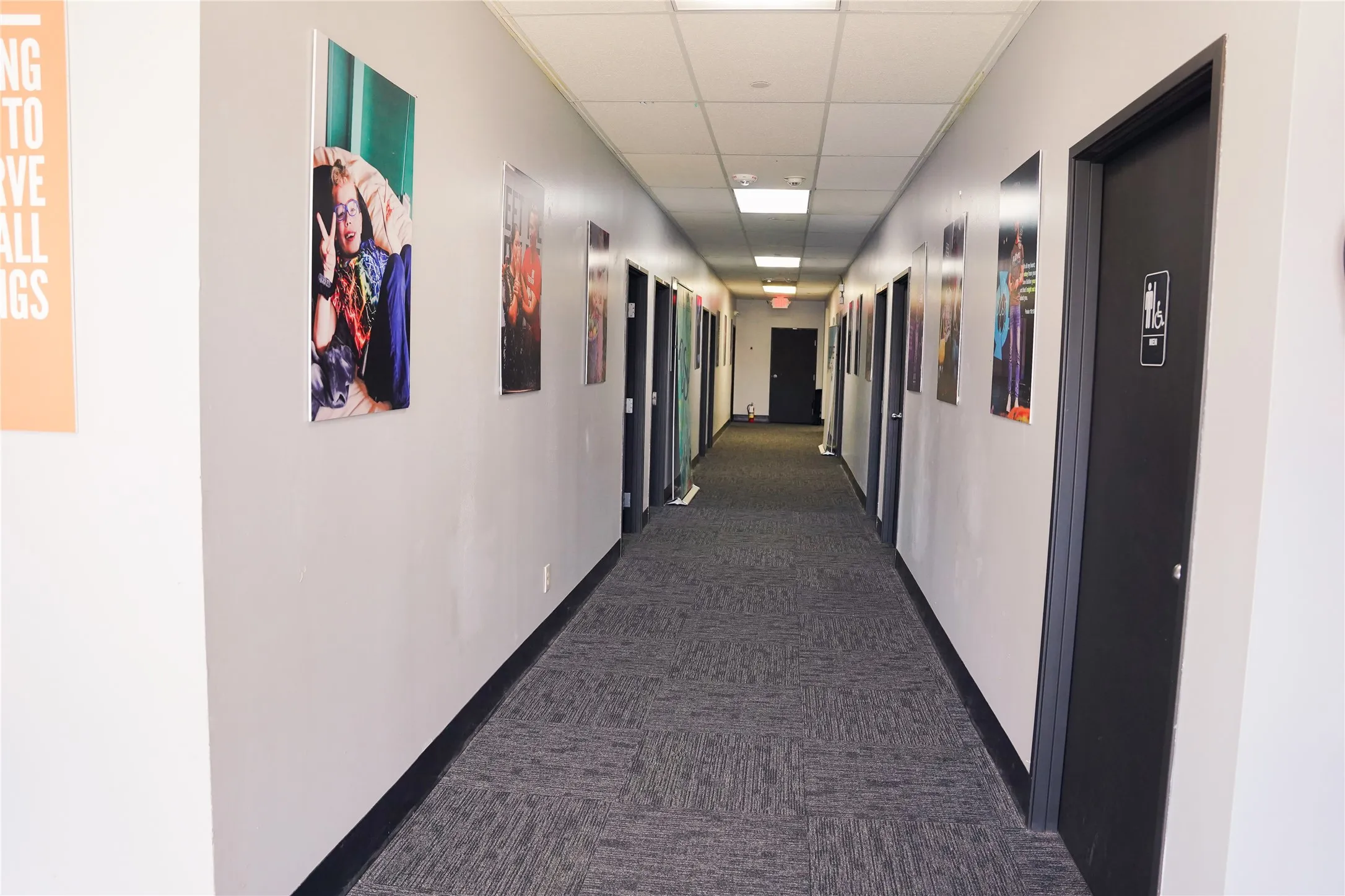 Recessed ceiling lighting, dropped ceiling, gray carpet flooring, white painted walls, and dark-paneled doors