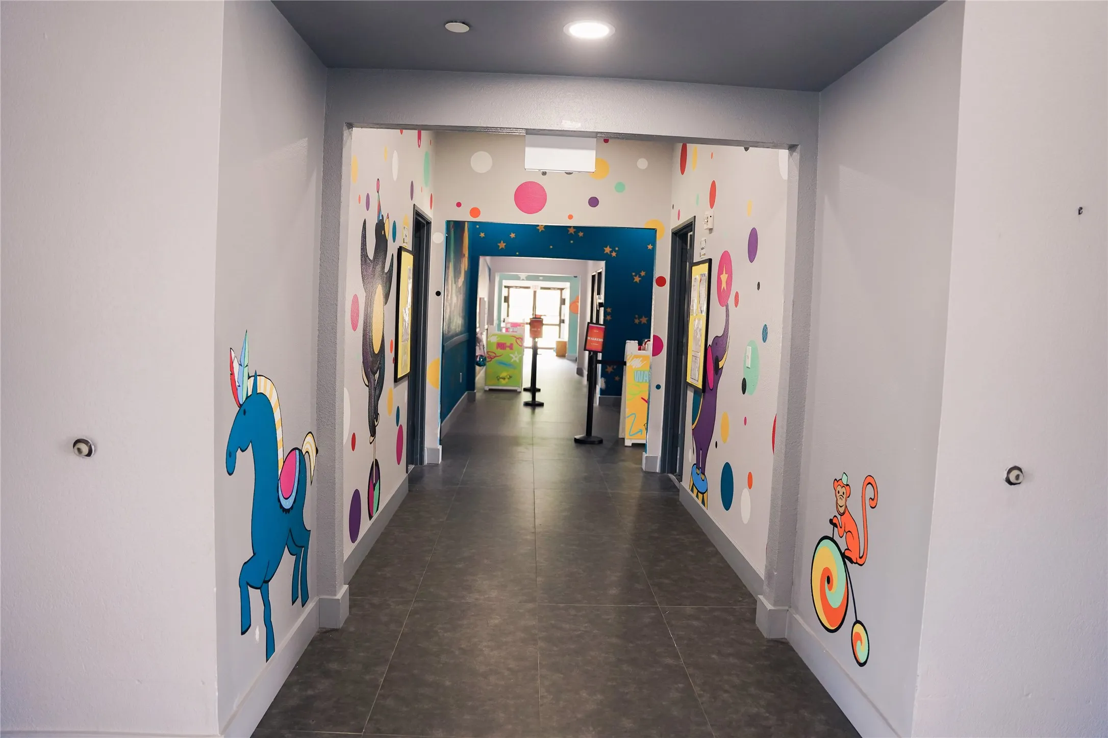 Hallway with grey flooring, recessed lighting, and colorful wall graphics