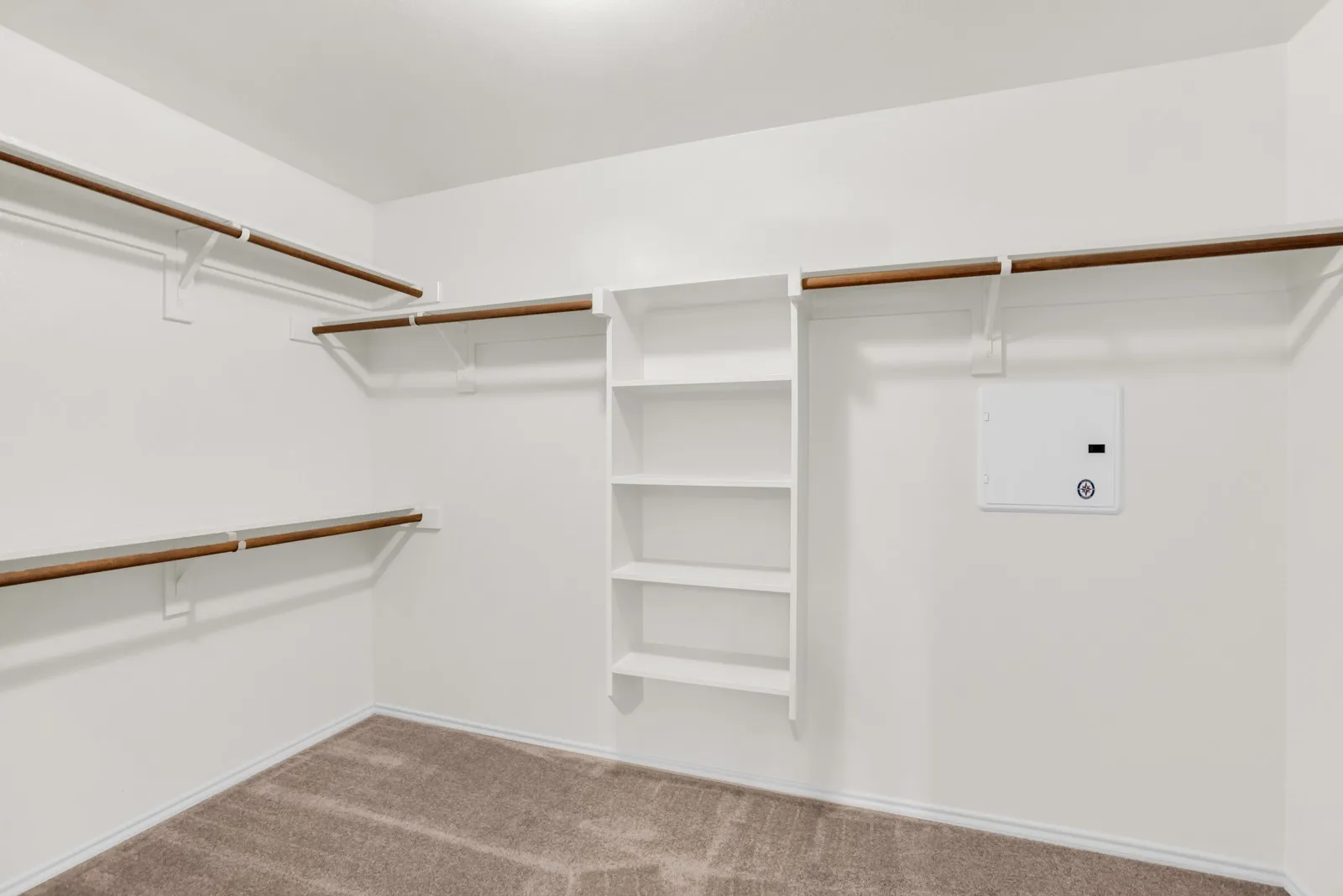 Walk-in closet with carpet flooring, white walls, built-in shelving, and multiple hanging rods