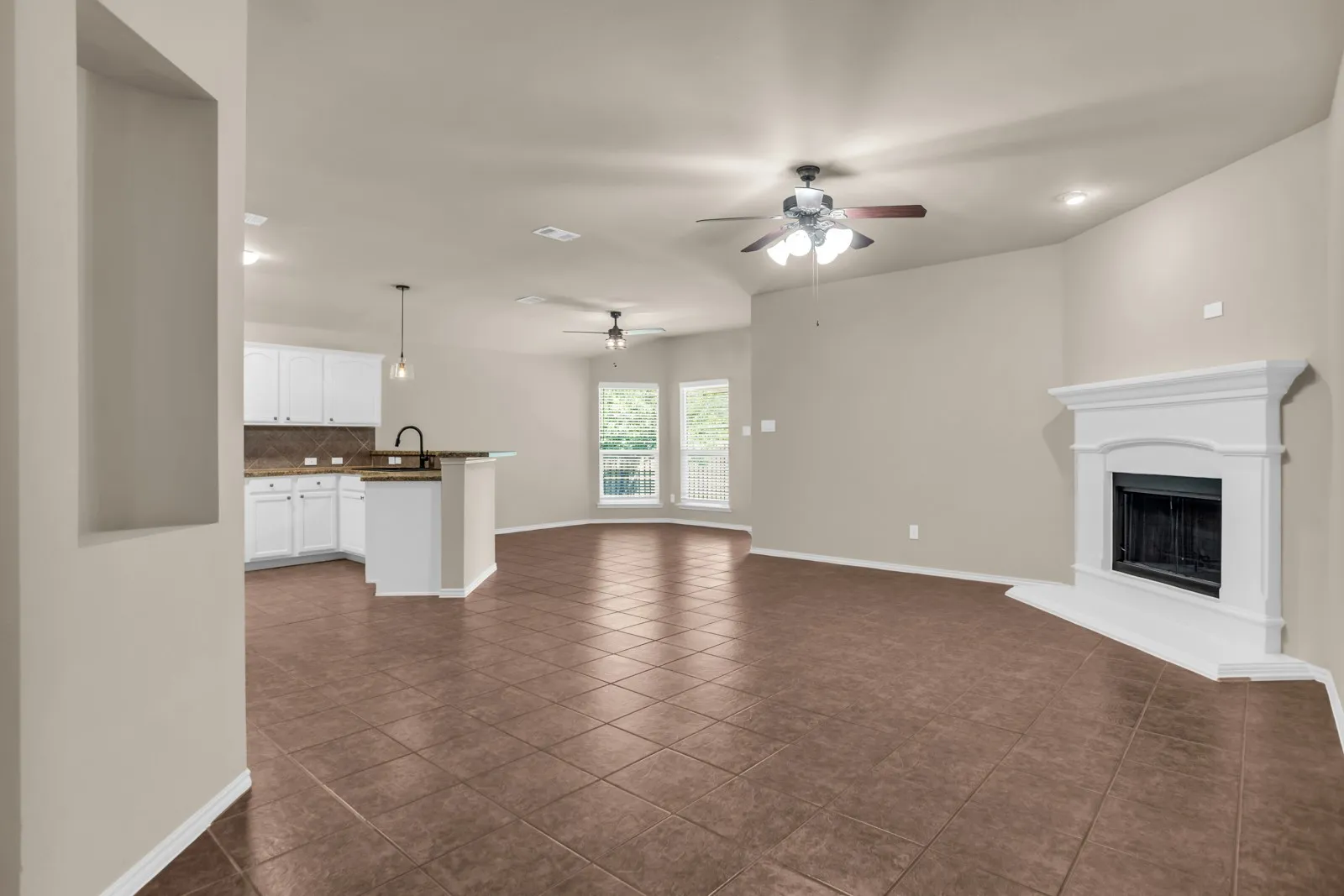 Expansive open living area featuring tile flooring, a fireplace with a white mantel, and ceiling fans