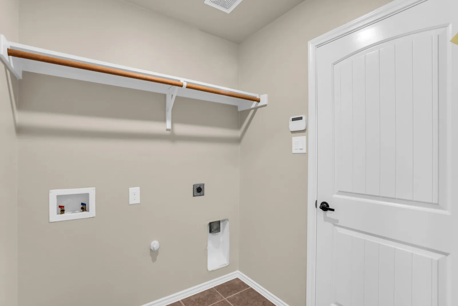 Dedicated utility space with durable tile flooring that leads to garage.