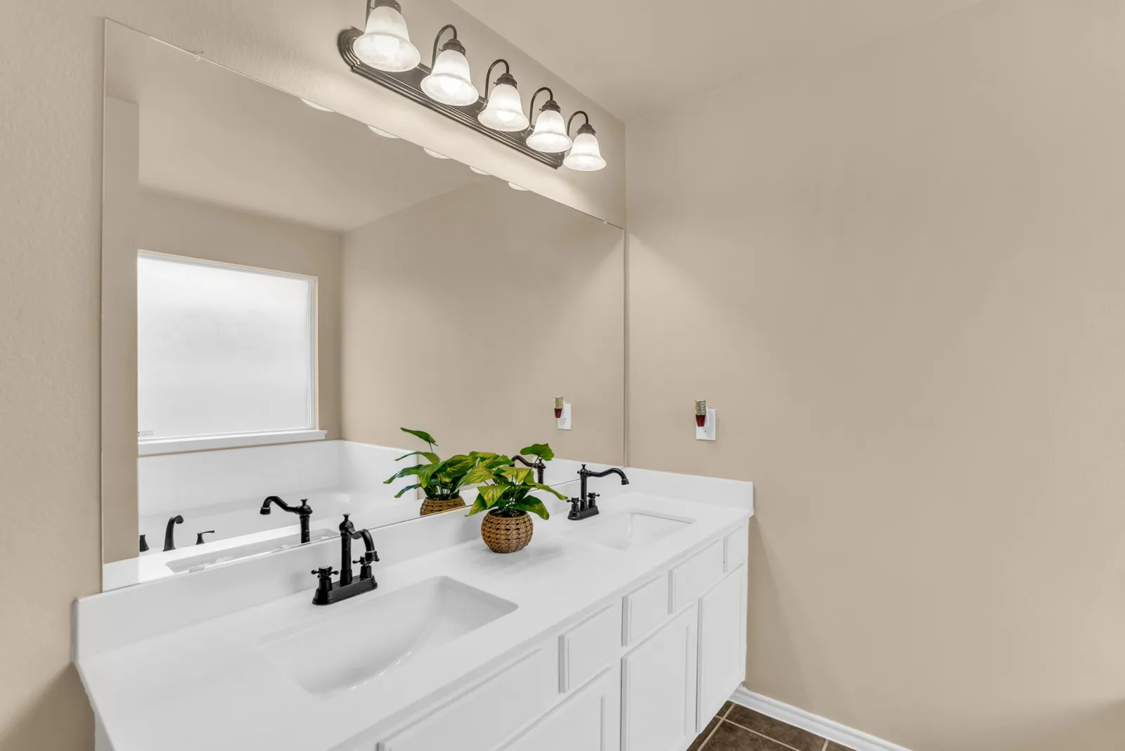 Completely update bathroom with double vanity with white integrated sinks, matte black hardware, and an expansive mirror
