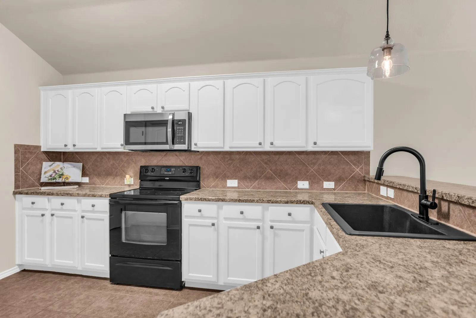 White cabinetry with arched panel doors, tile backsplash, black range, and stainless steel microwave
