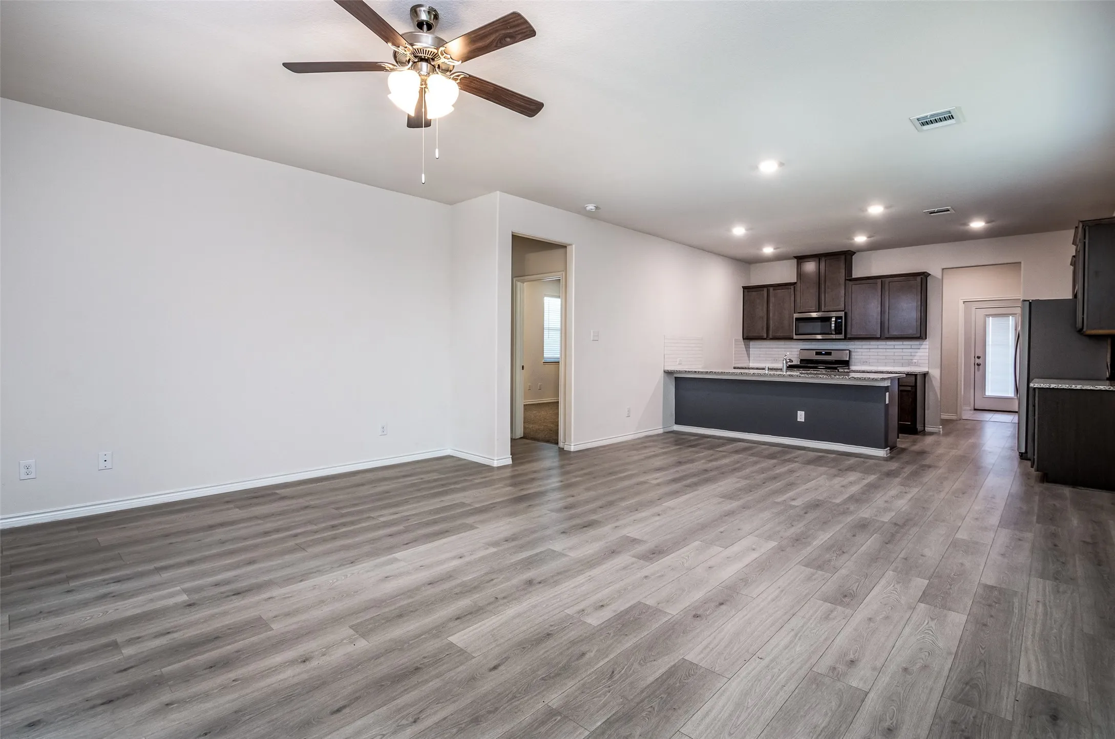 Open-concept living space featuring wood-finish flooring, recessed lighting, and a ceiling fan