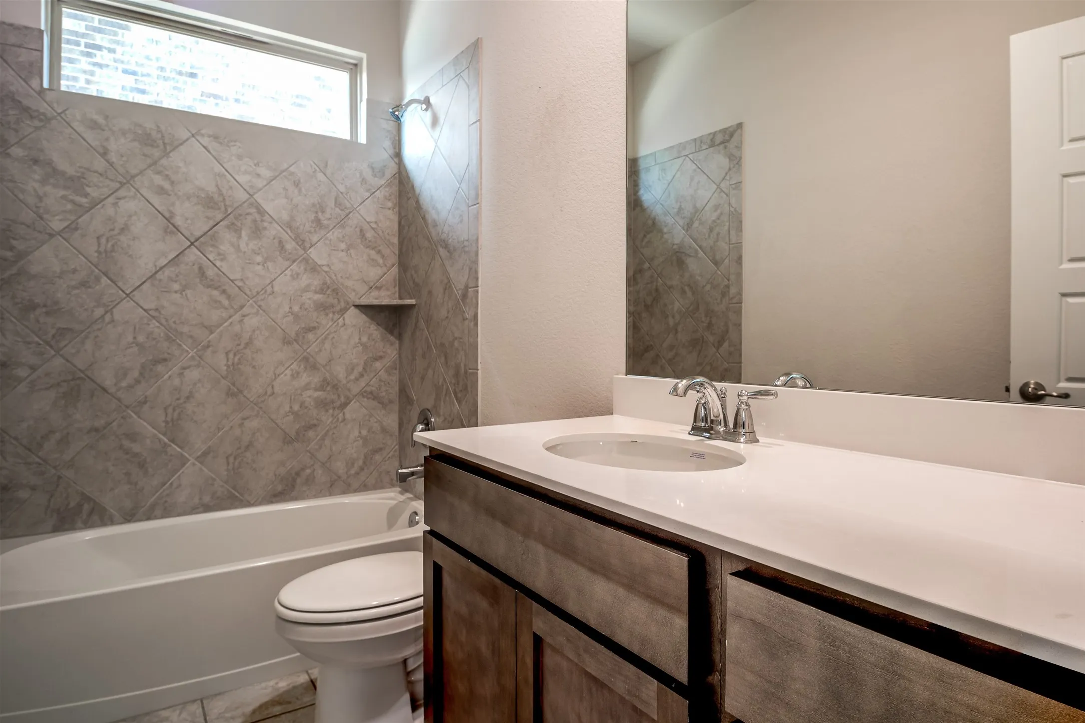 Bathroom featuring a wood-finish vanity with a white countertop, an undermount sink, and a chrome faucet
