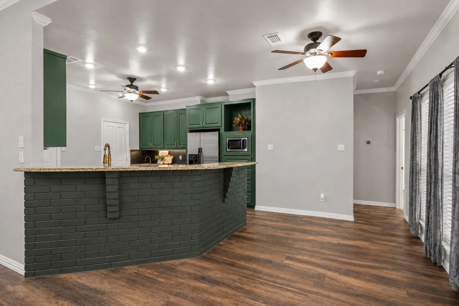 Kitchen featuring green cabinetry, stainless steel appliances, a breakfast bar with a stone-finish countertop, recessed lighting, and wood-finish flooring