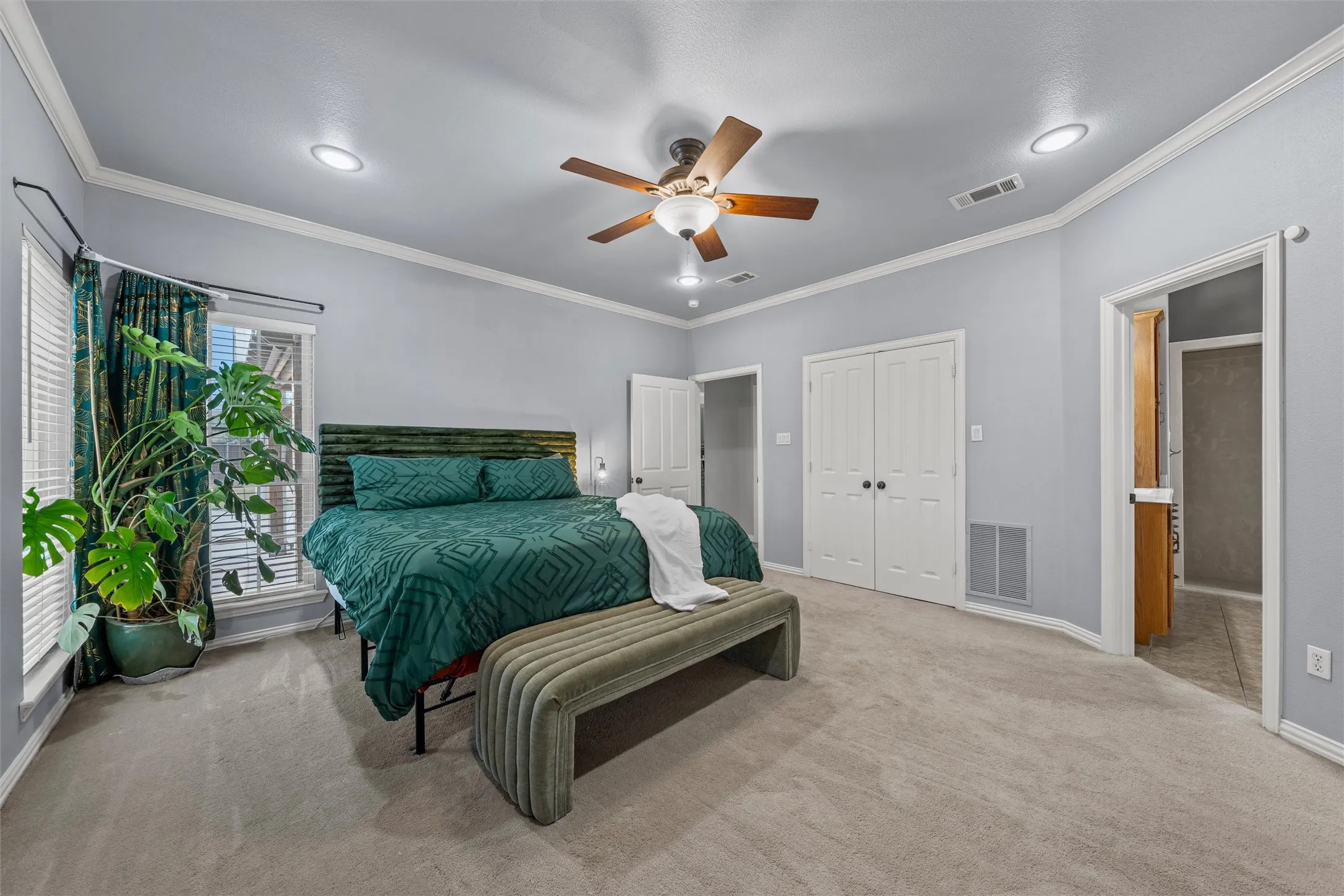 Wall-to-wall carpeting, vaulted ceiling with a ceiling fan, recessed lighting, double-door closet, and an attached bathroom with tile flooring