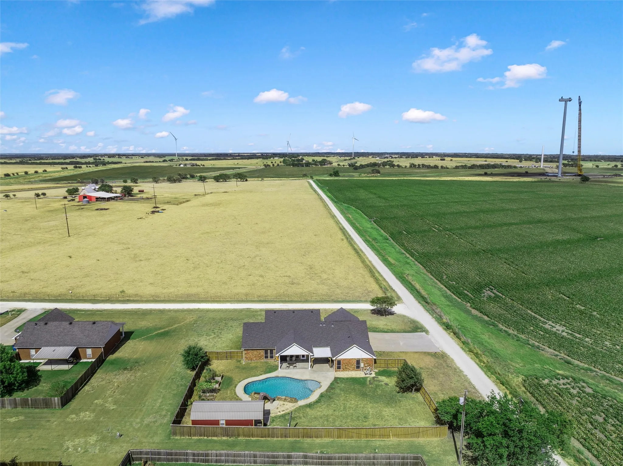 Single-story residence with a dark shingle roof, attached covered patio, and fenced backyard featuring an in-ground swimming pool