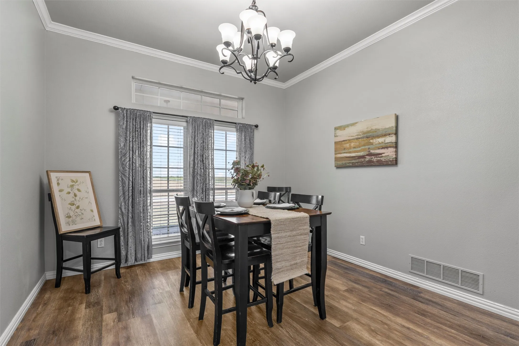 Vaulted ceiling with crown molding, wood-finish flooring, and a chandelier lighting fixture