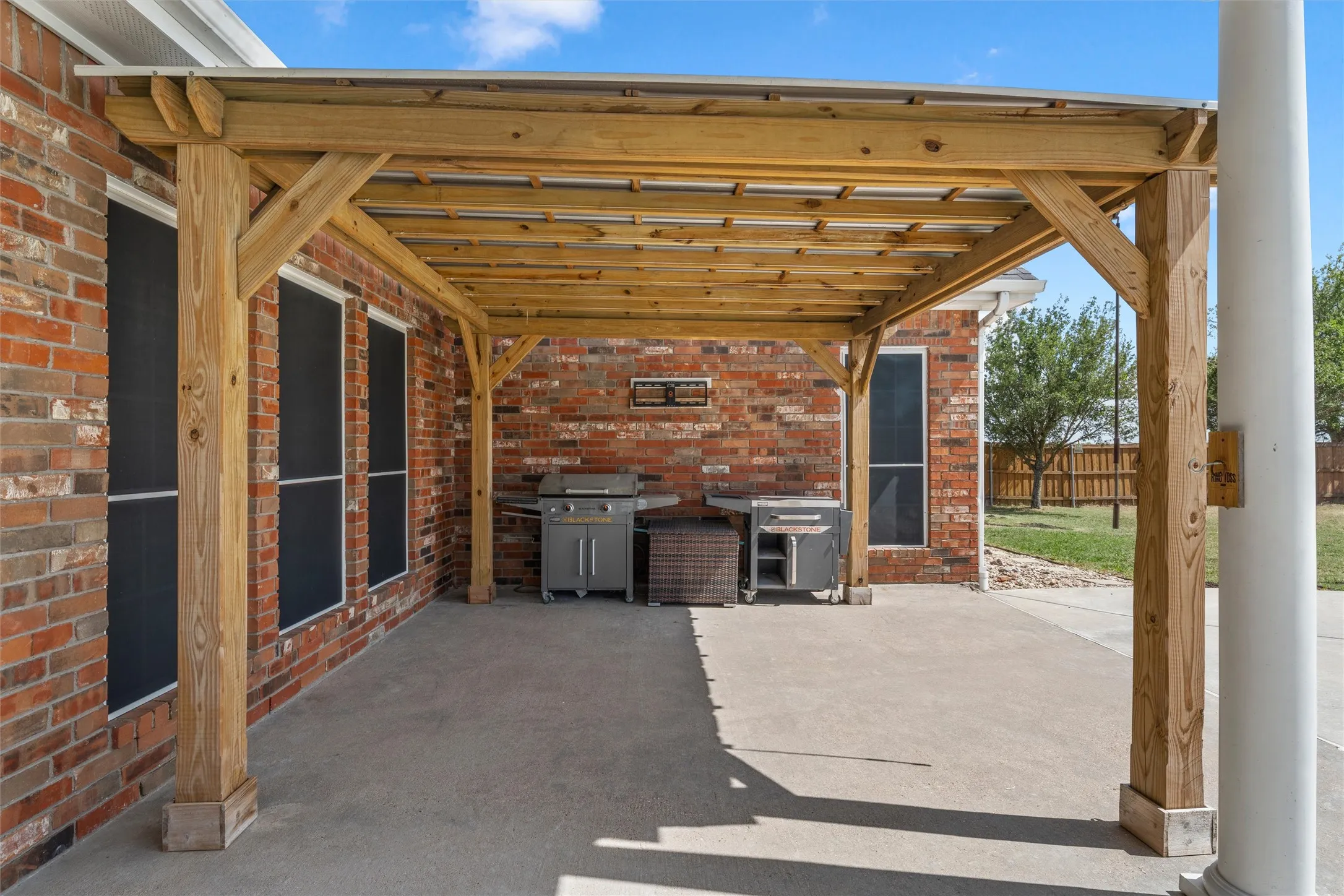 Wood pergola with a translucent roof over a concrete patio