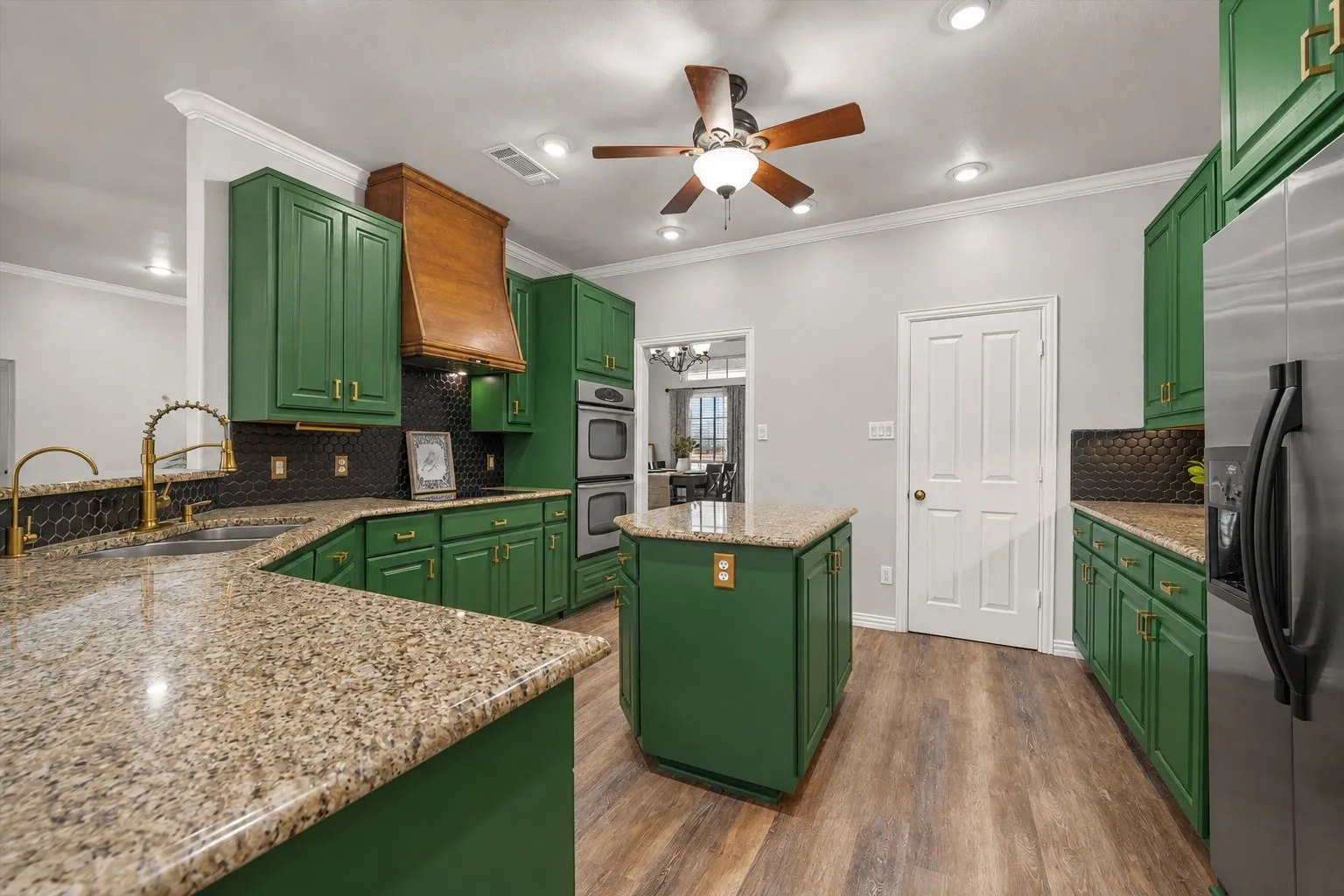 Kitchen featuring green cabinetry, light-toned countertops, a central island, wood-finish flooring, and recessed ceiling lighting