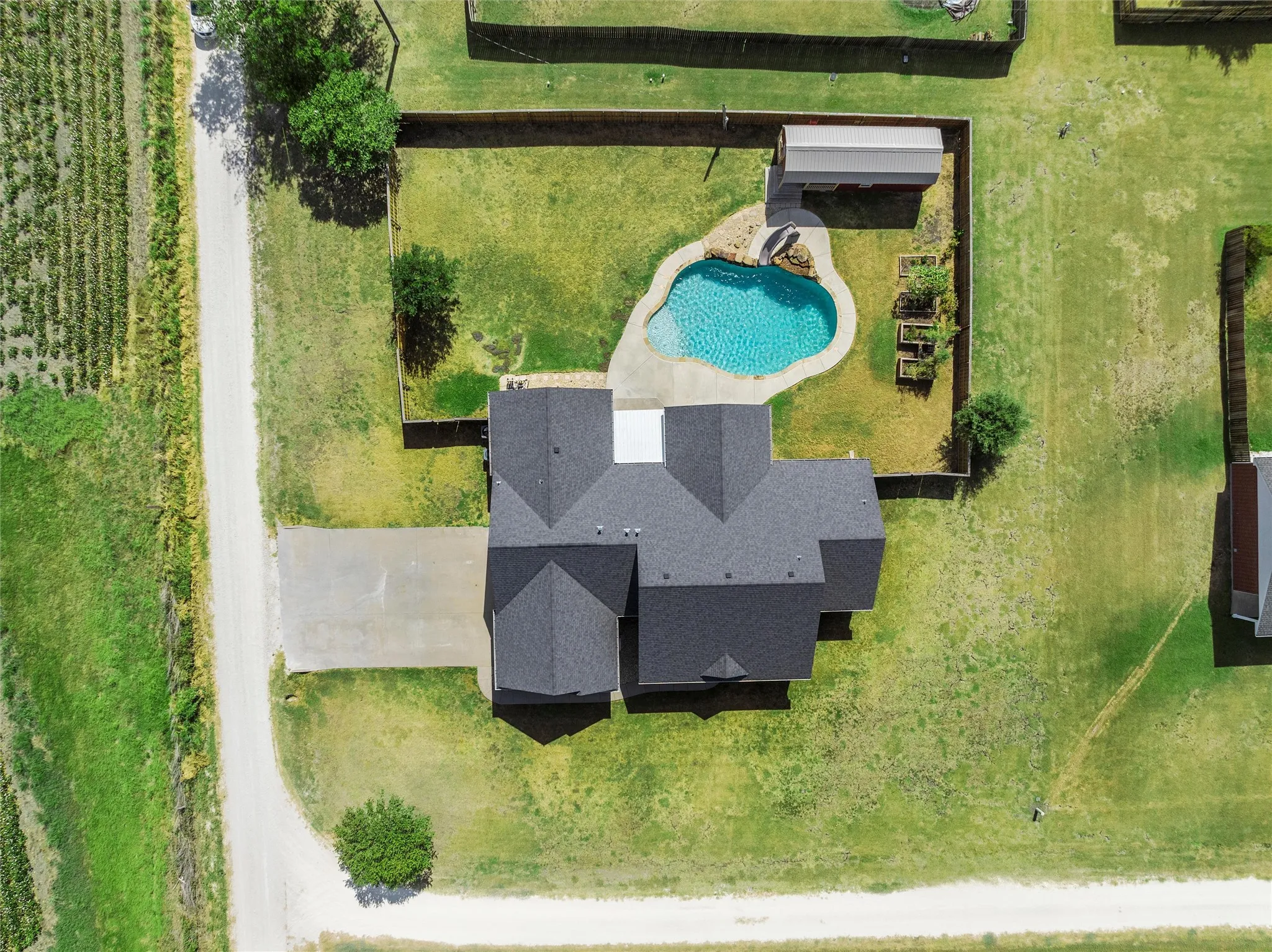 Manicured landscaping, fenced yard, paved driveway, pool, and detached structure