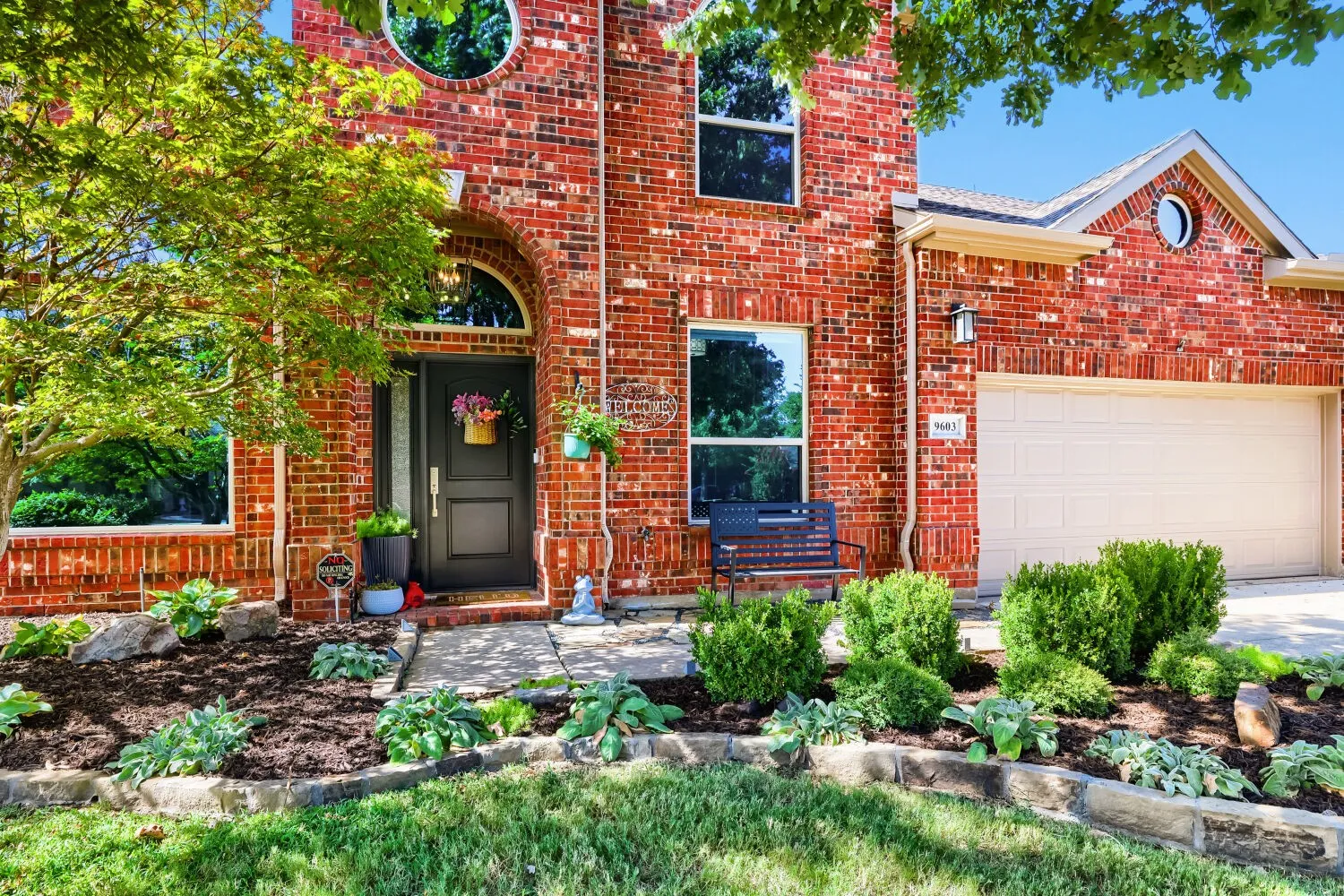 Beautifully landscaped front yard featuring a mature Burr Oak tree that provides substantial shade from the Texas sun.