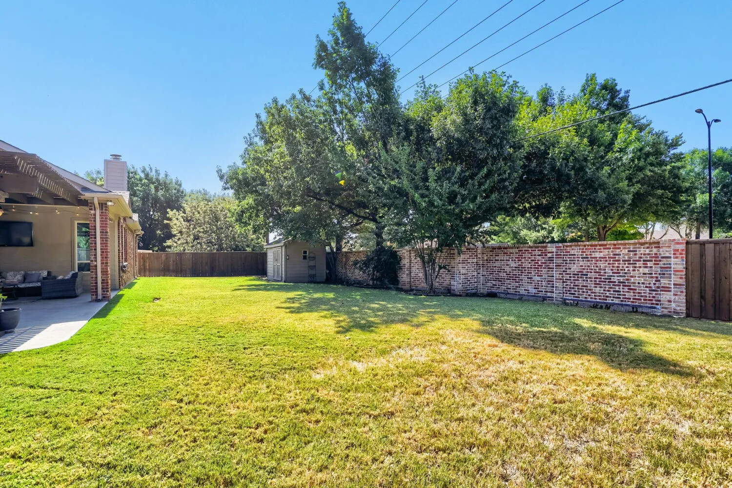 Spacious backyard featuring a combination brick and wood fence for enhanced privacy and a storage shed.