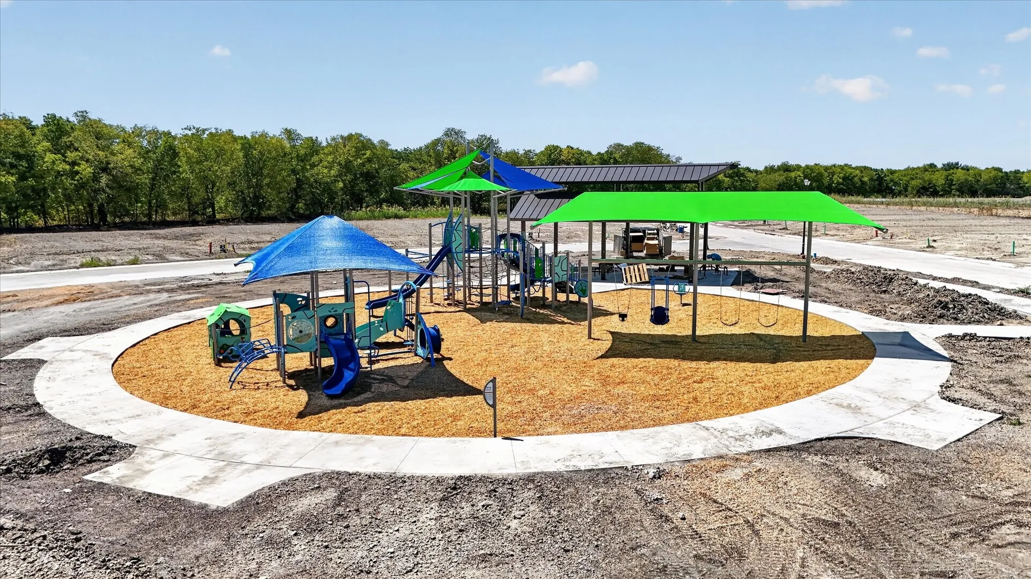 Recreational area featuring a playground with slides, multiple swings, and protective shade​​‌​​​​‌​​‌‌​‌‌​​​‌‌​‌​‌​‌​​​‌​​ structures