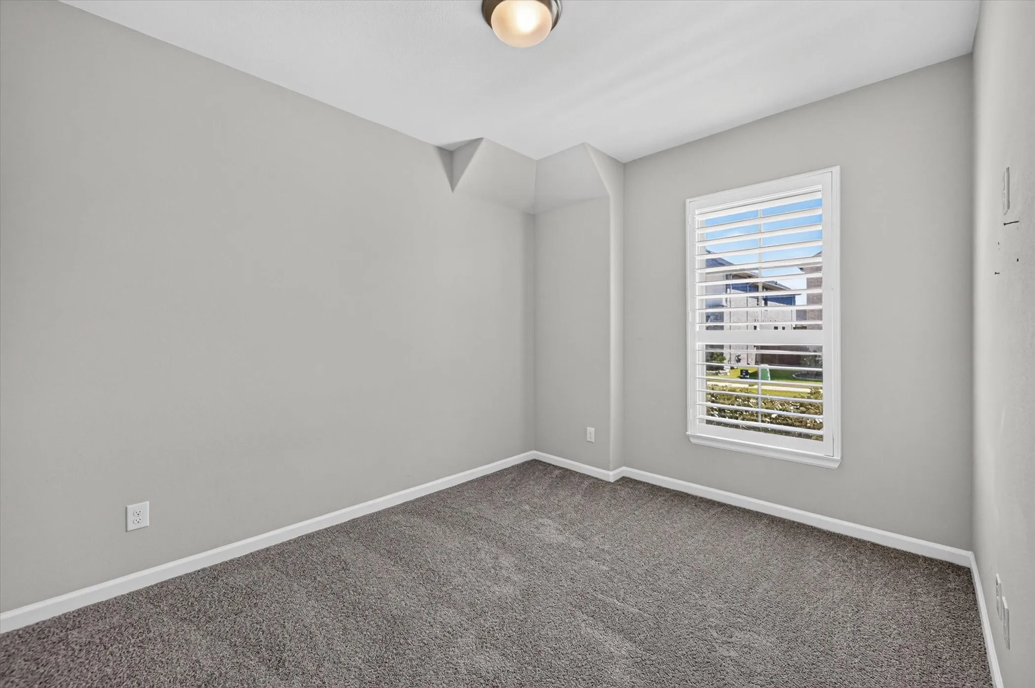 Neutral wall color, window with horizontal blinds, overhead flush mount light fixture, and carpet flooring