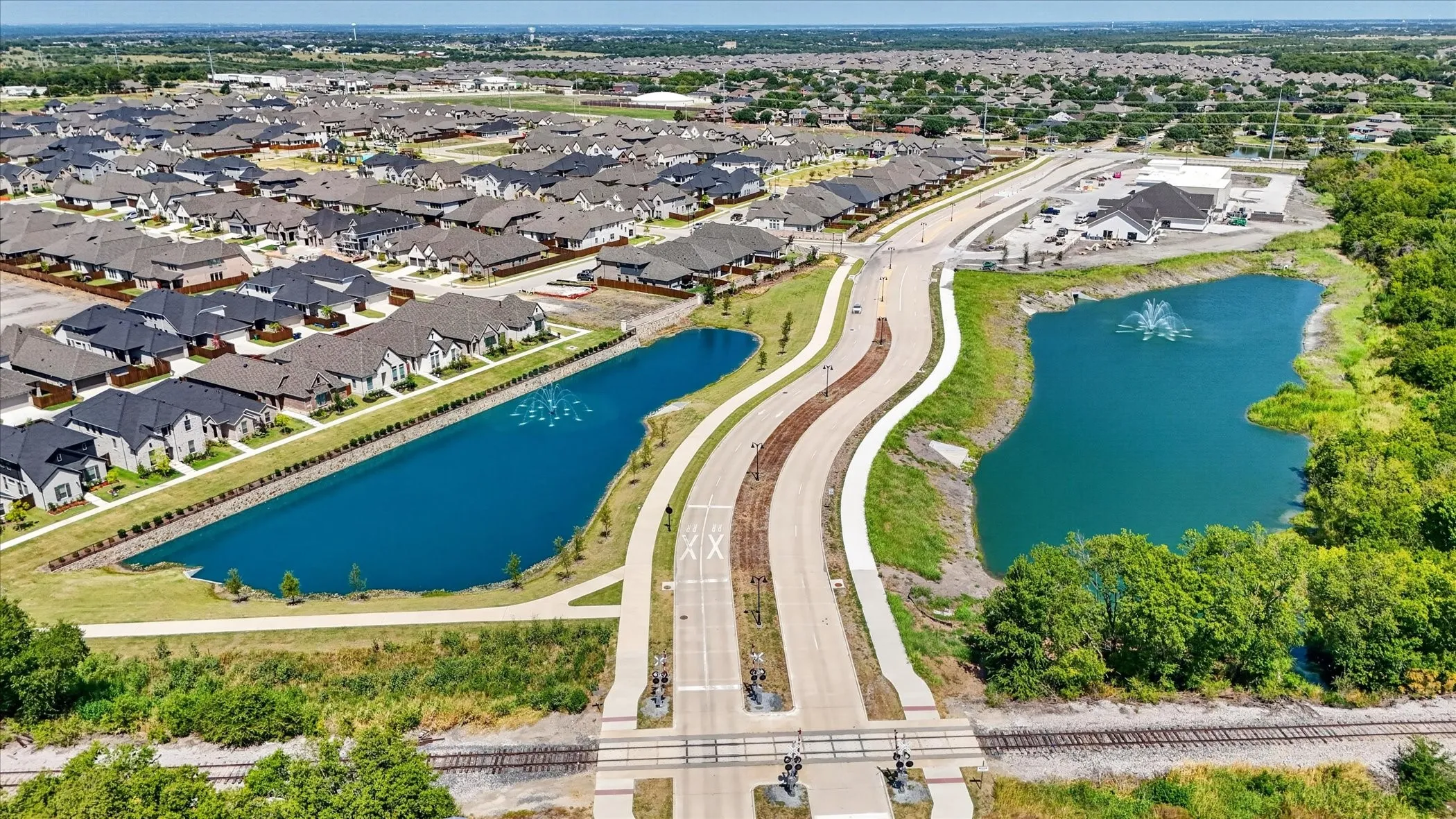 Newly developed residential area featuring multiple ponds, a water feature, and established roads