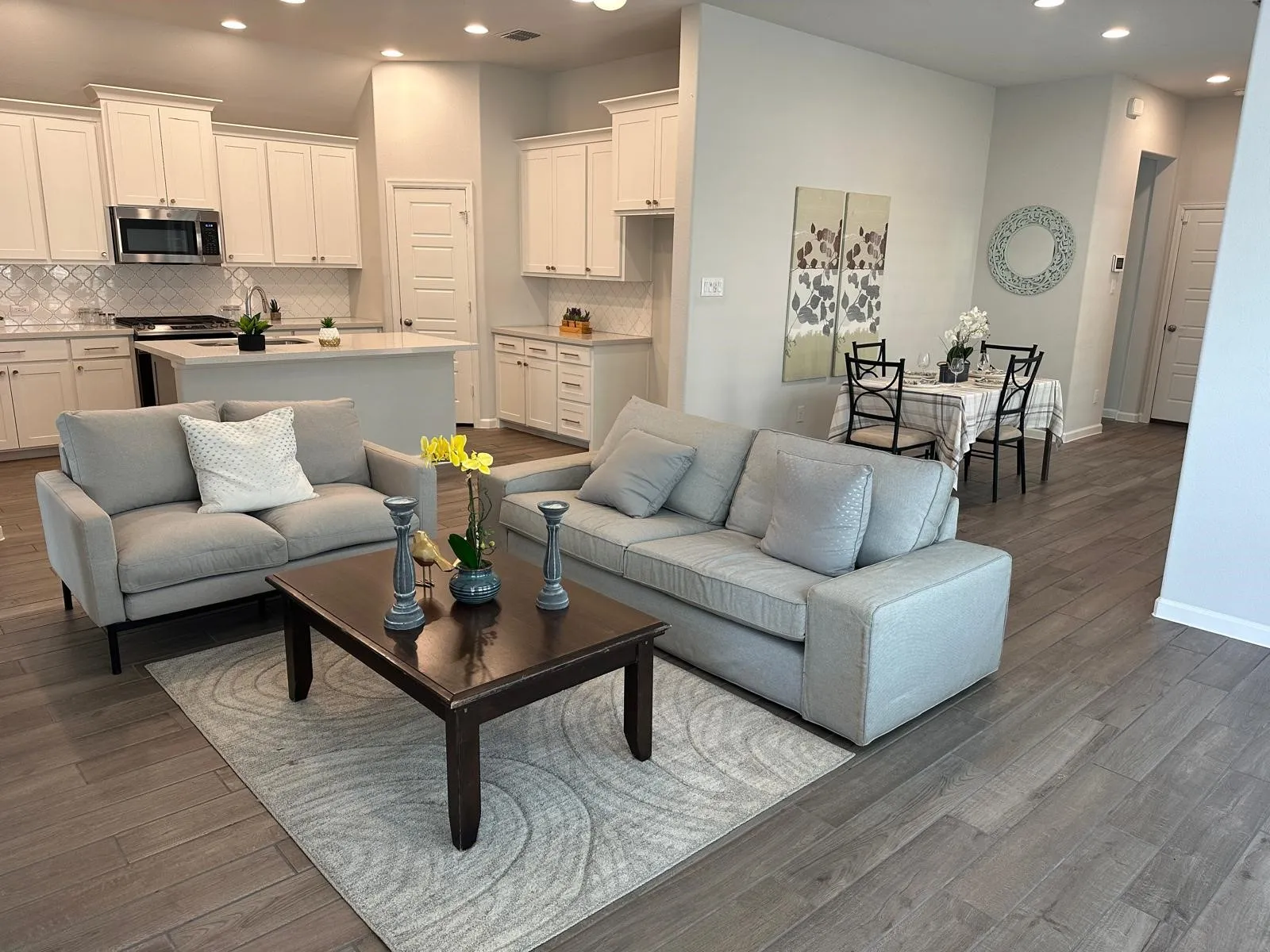 Open-concept living space featuring wood-finish flooring, recessed lighting, and a kitchen with white cabinetry, a center island, and stainless steel appliances