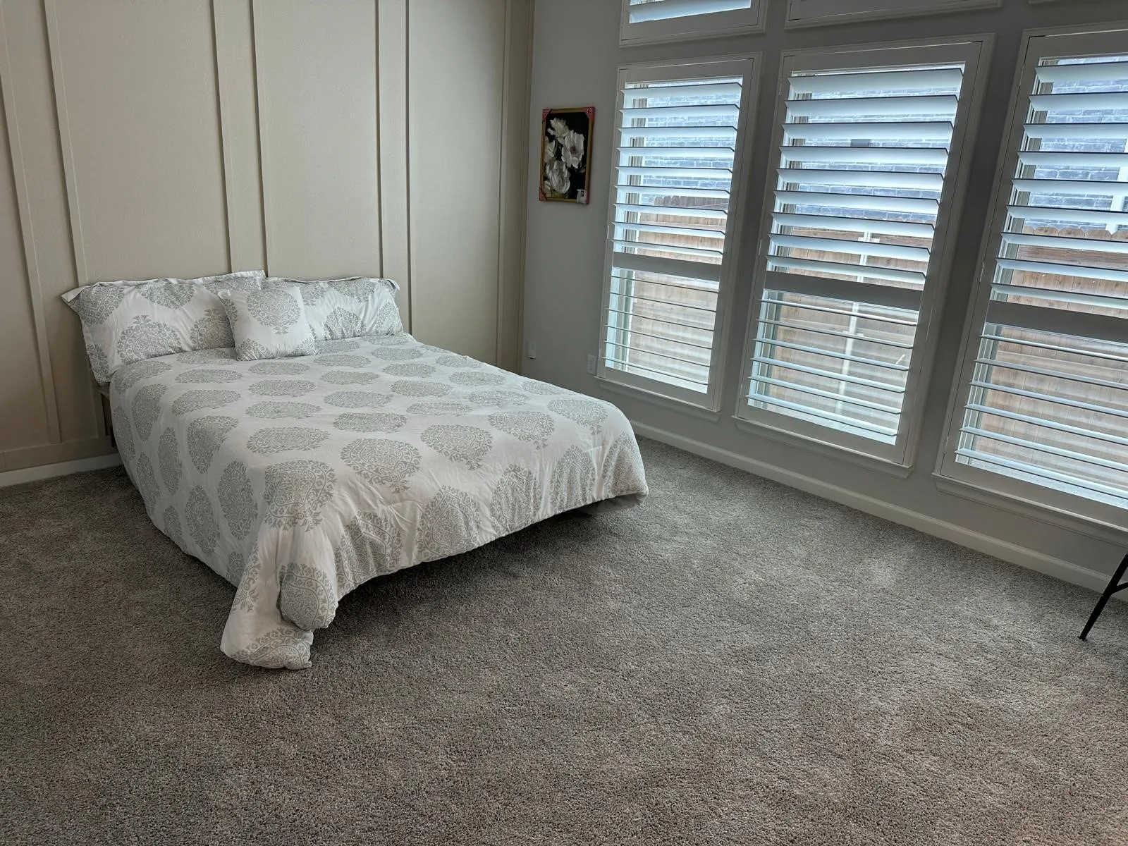 Wall-to-wall carpeting with vertical wall paneling, featuring a series of tall windows with plantation shutters