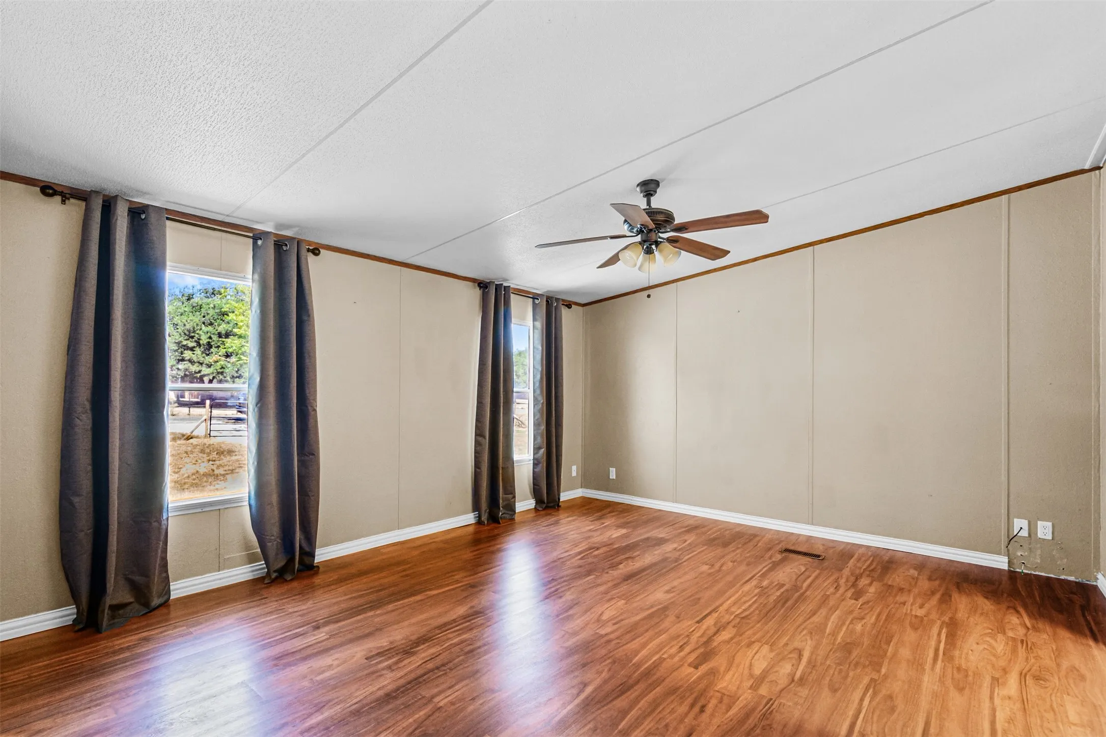 Wood-finish flooring, ceiling fan with integrated lighting, and multiple windows