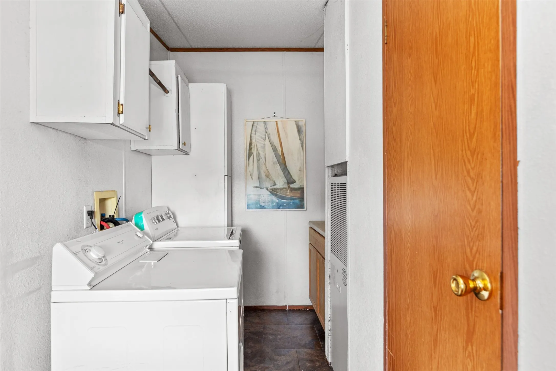 Built-in overhead white cabinetry, wood-finish door, and wood-finish flooring