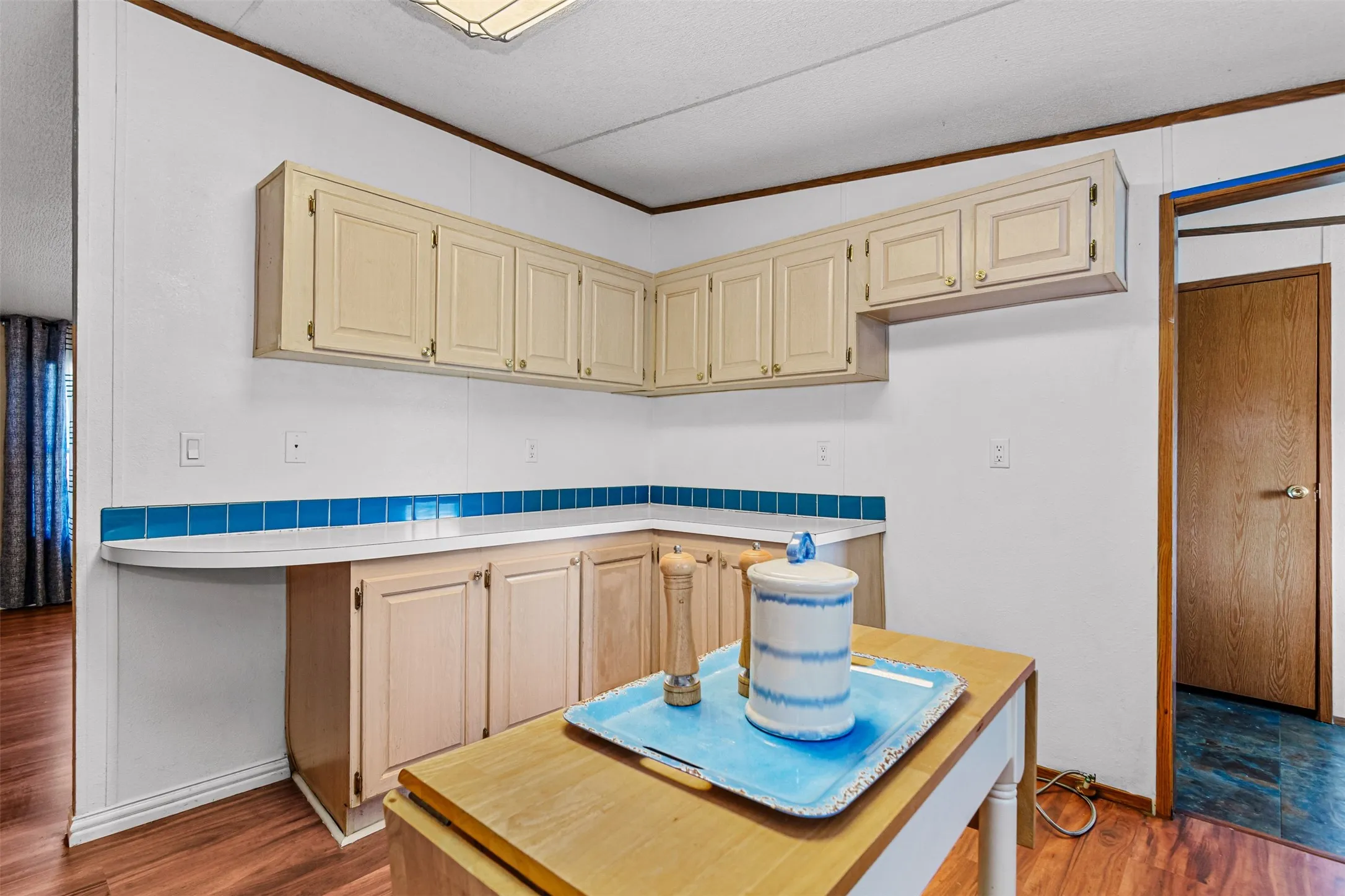 White cabinetry with gold-tone hardware, white countertops, and a blue tile backsplash