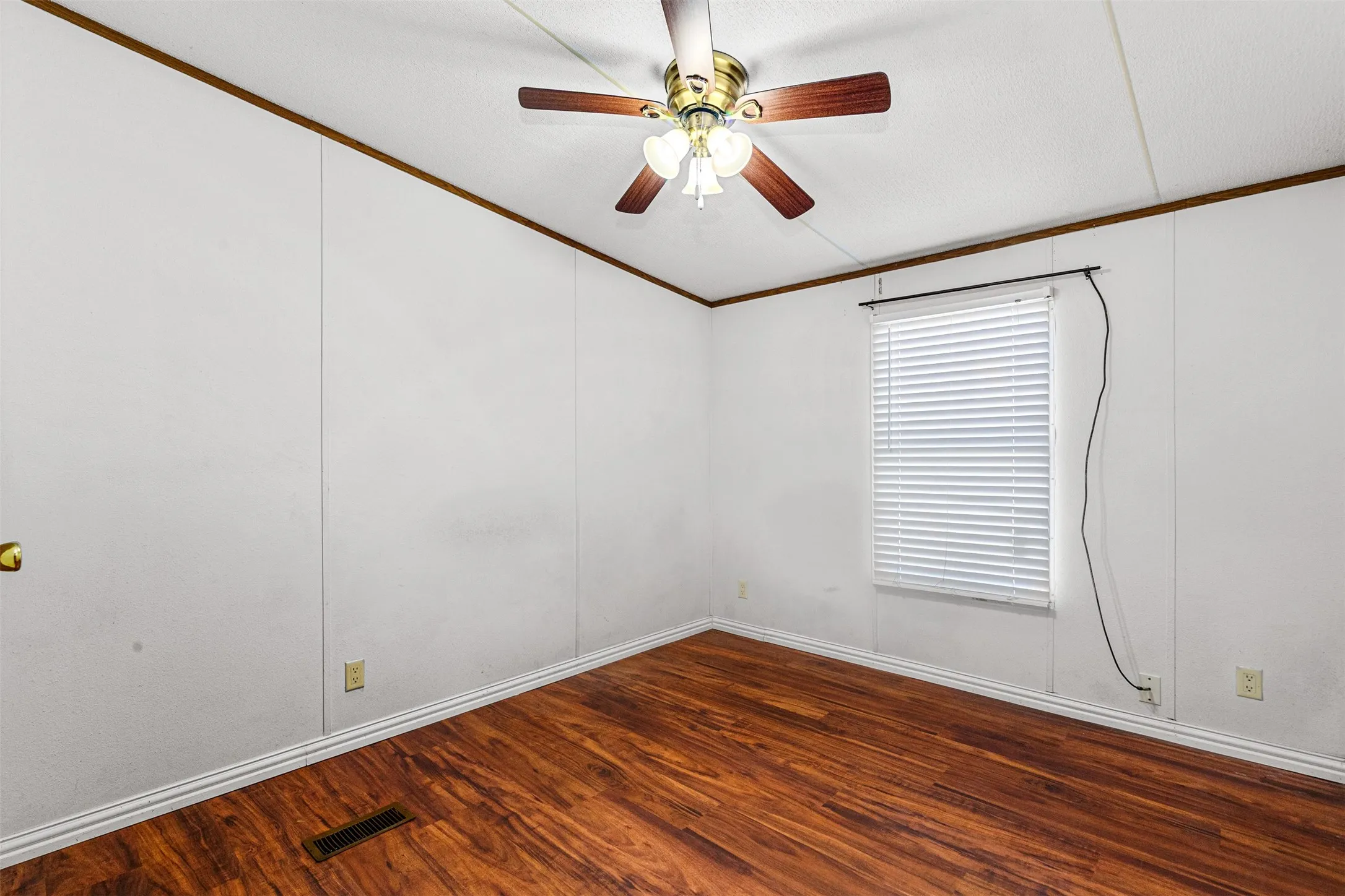 Wood-finish flooring with white baseboards, a window with horizontal blinds, and a ceiling fan with integrated lighting