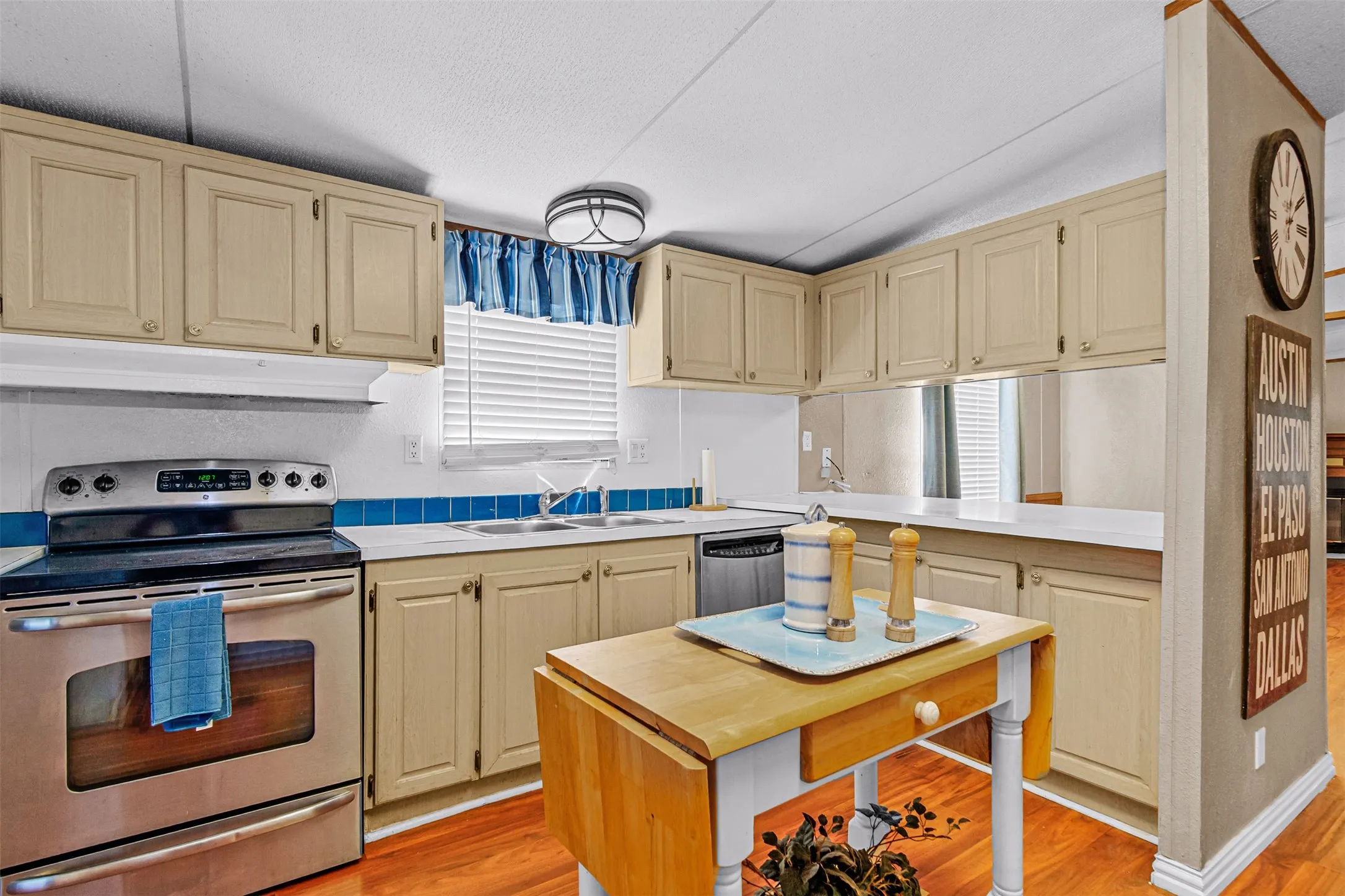 Kitchen featuring stainless steel range, light-toned cabinetry, white countertops, tile backsplash, and wood-finish flooring