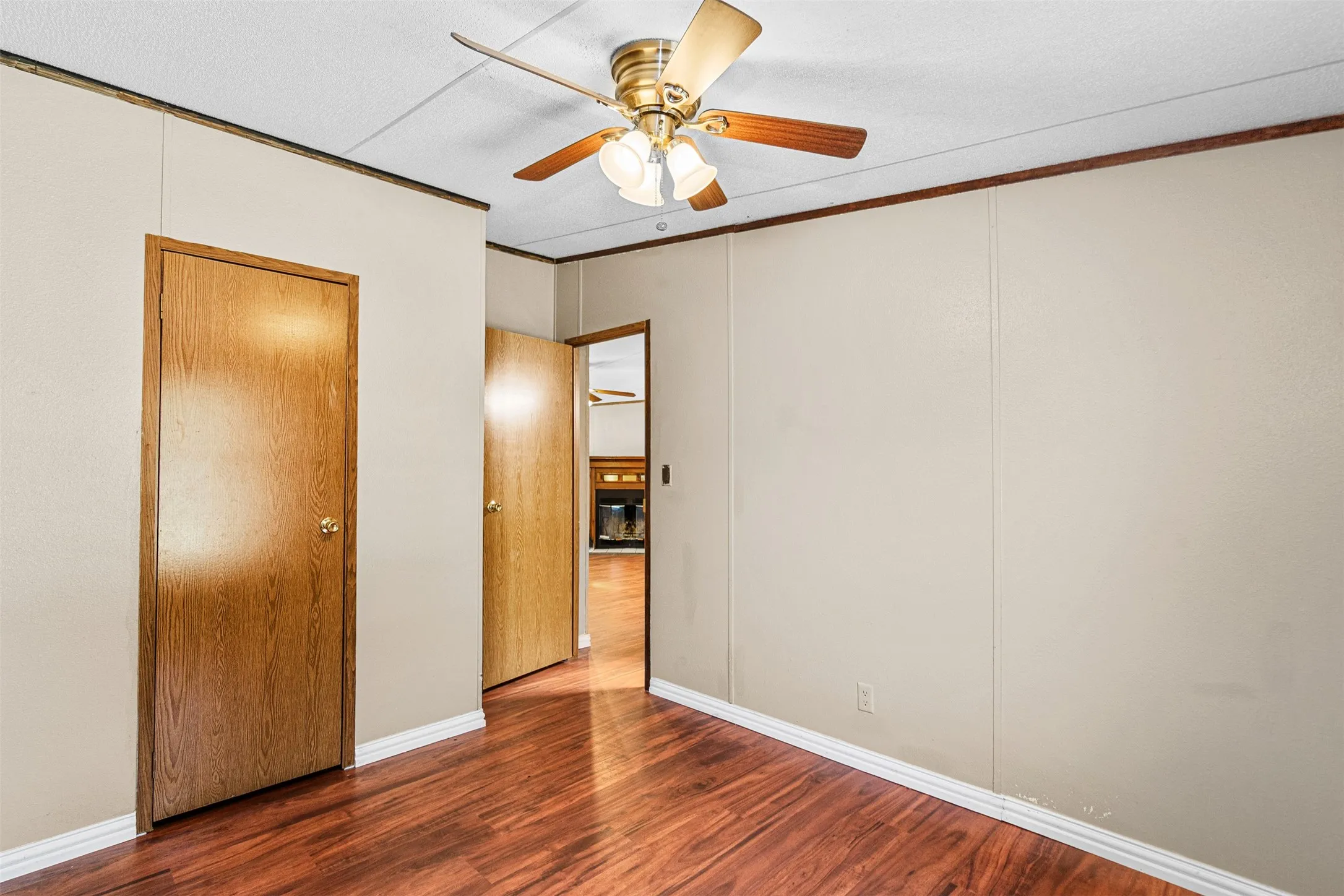 Wood-finish flooring, paneled walls, and a ceiling fan with integrated lighting
