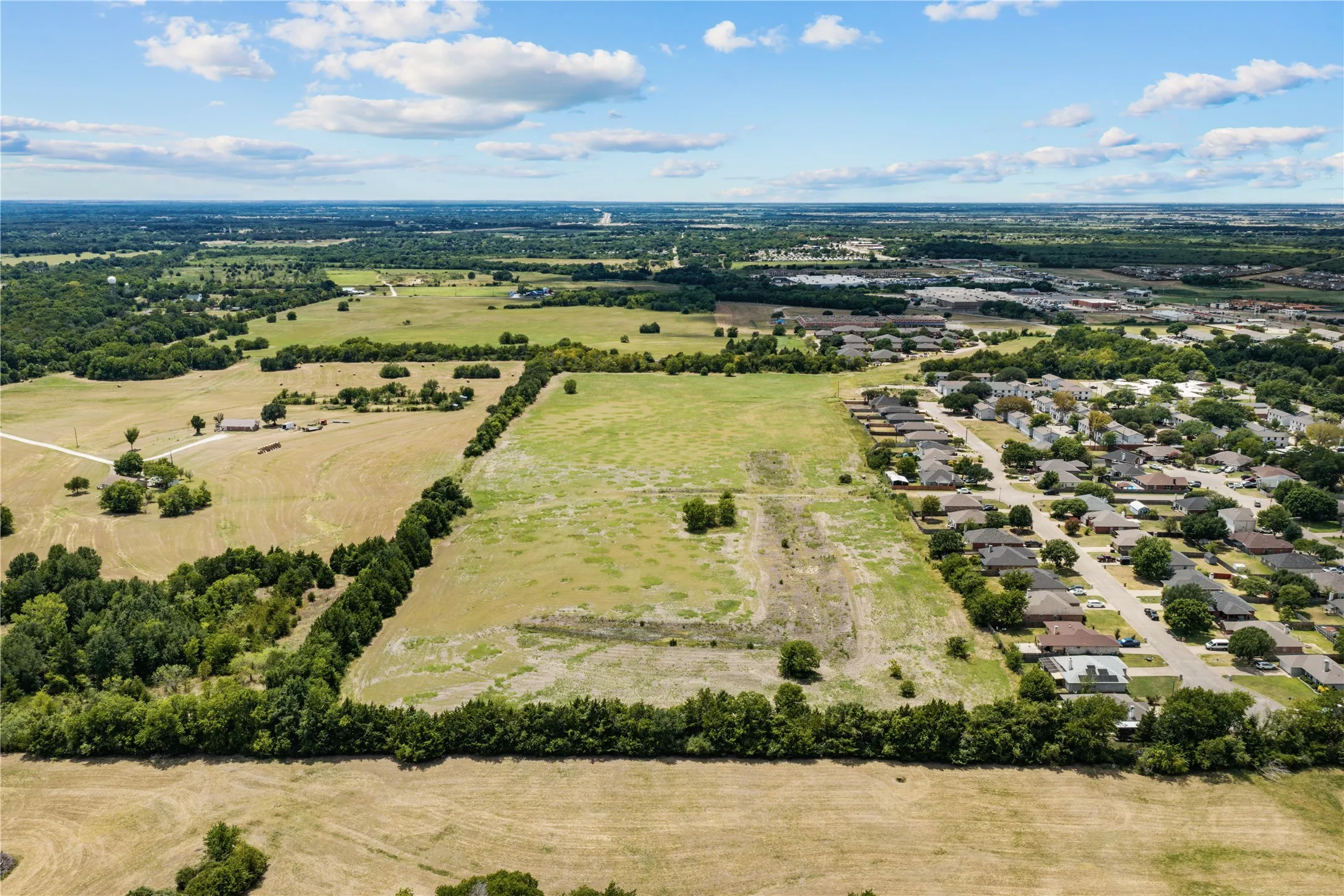 Expansive undeveloped land featuring mature tree lines and a clear perimeter