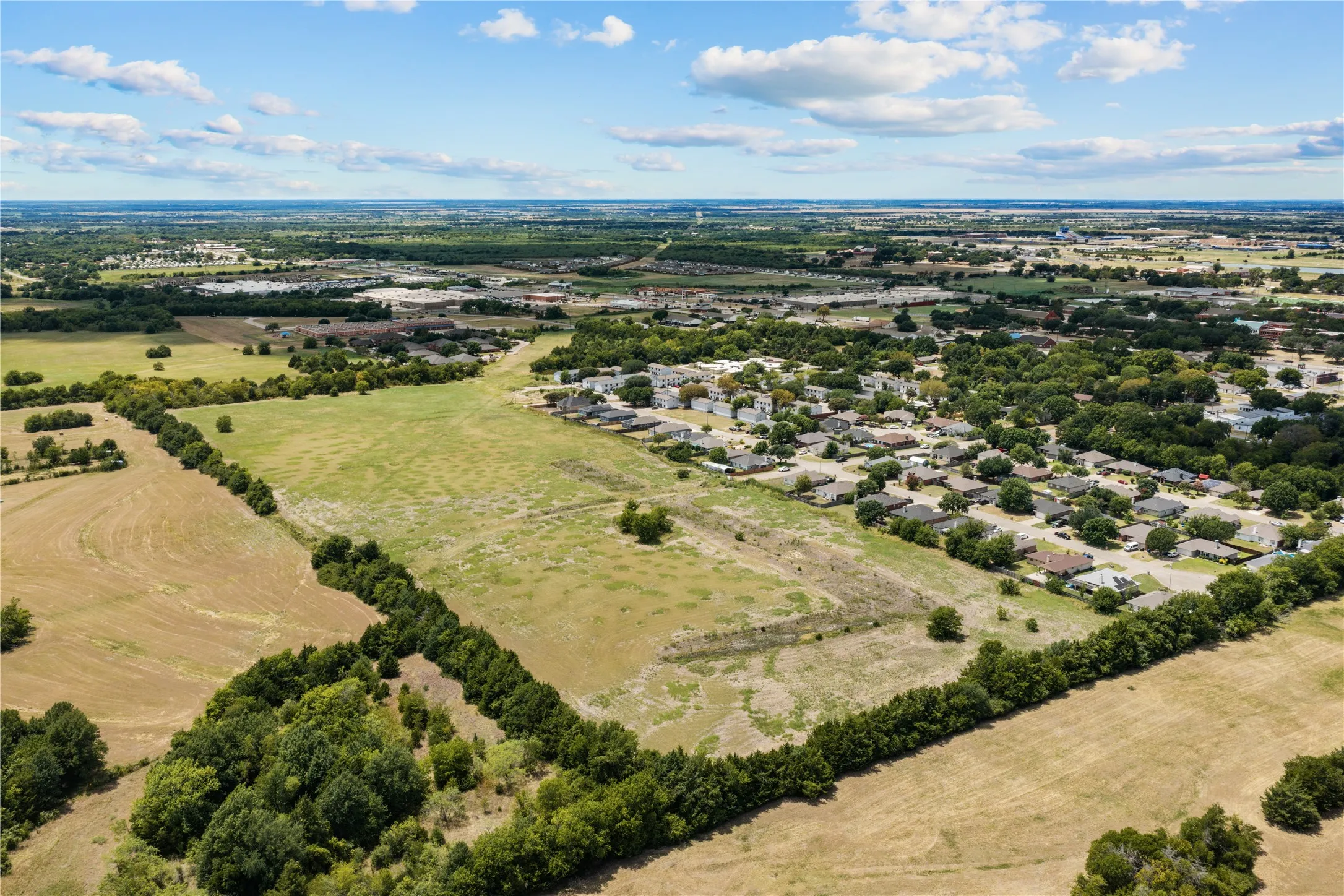 Expansive open land area with established tree lines