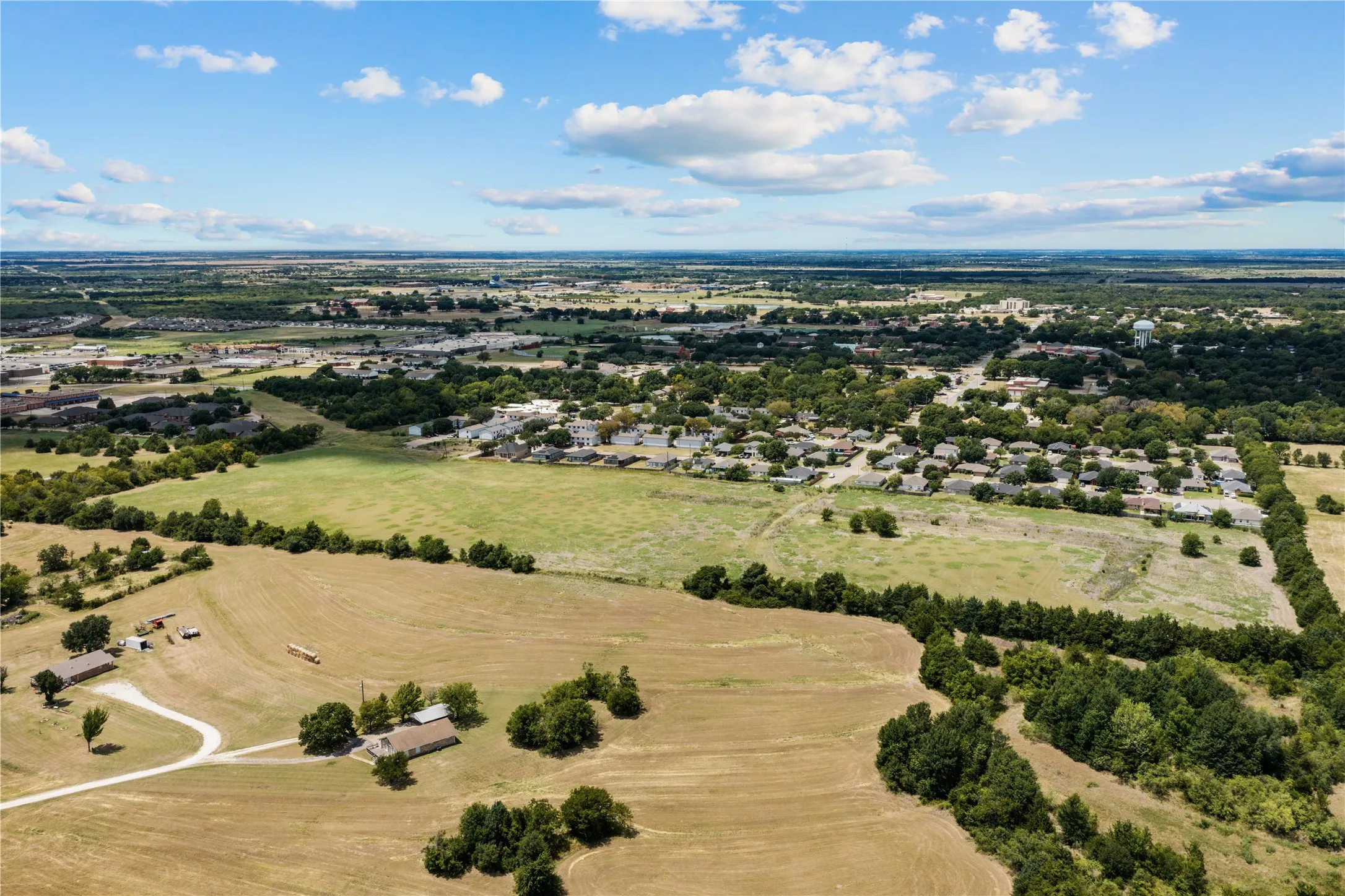 Expansive rural landscape featuring a mix of cultivated fields and wooded areas