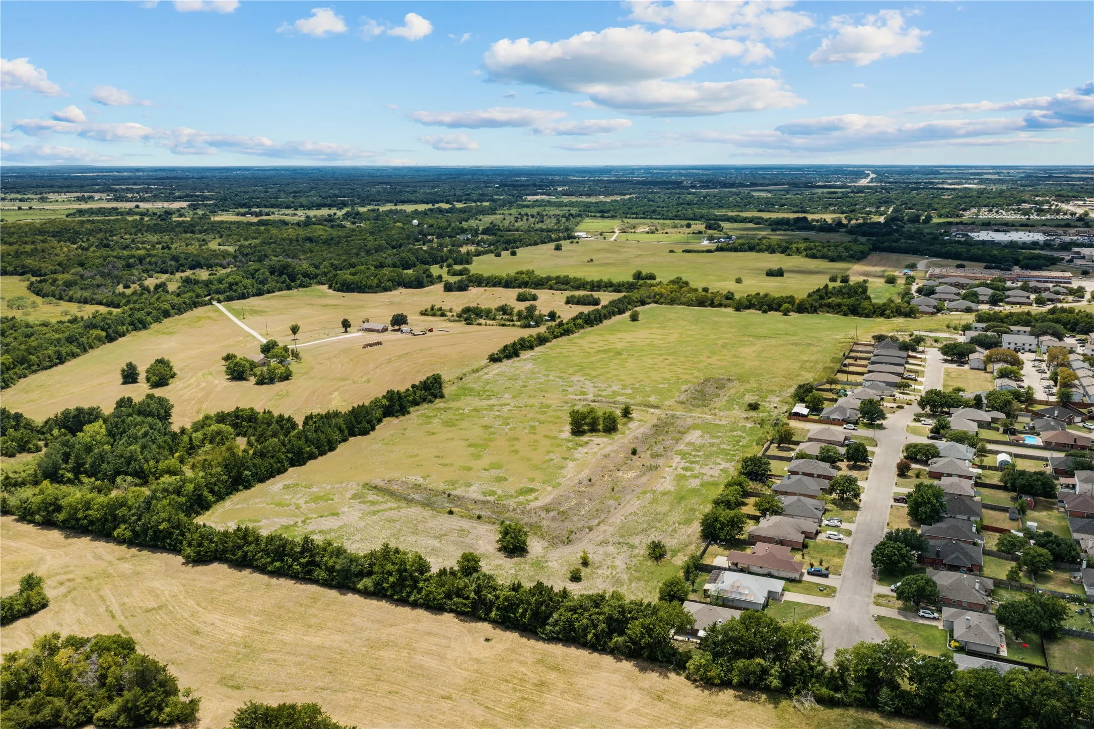 Expansive land parcel with surrounding wooded areas