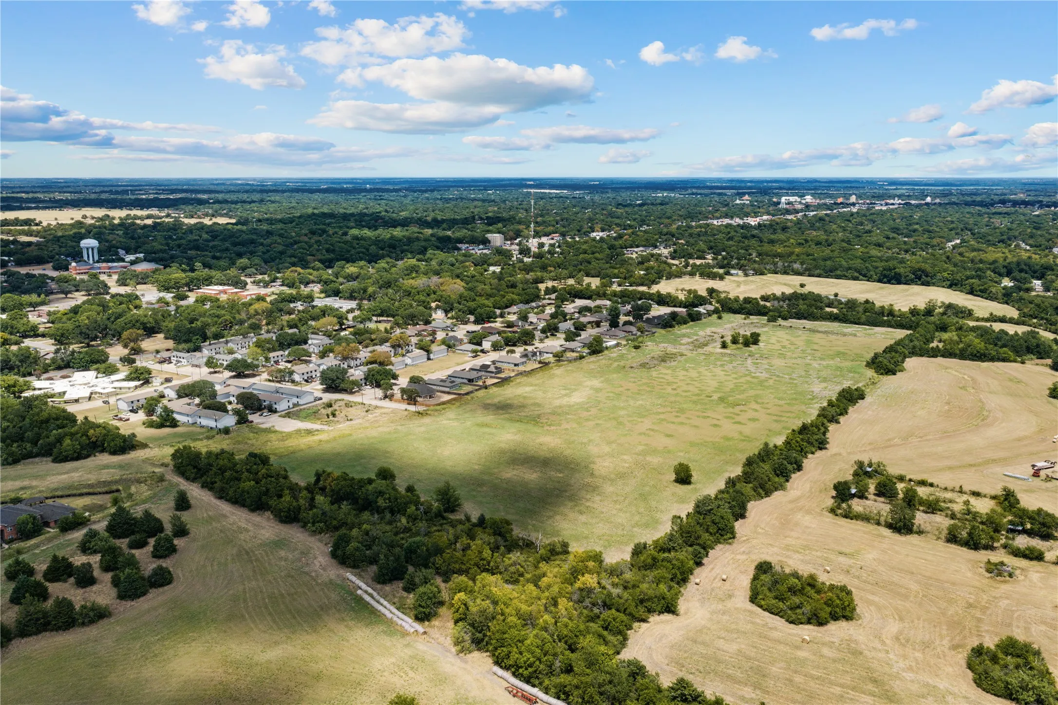 Expansive land parcel featuring open fields and mature tree lines