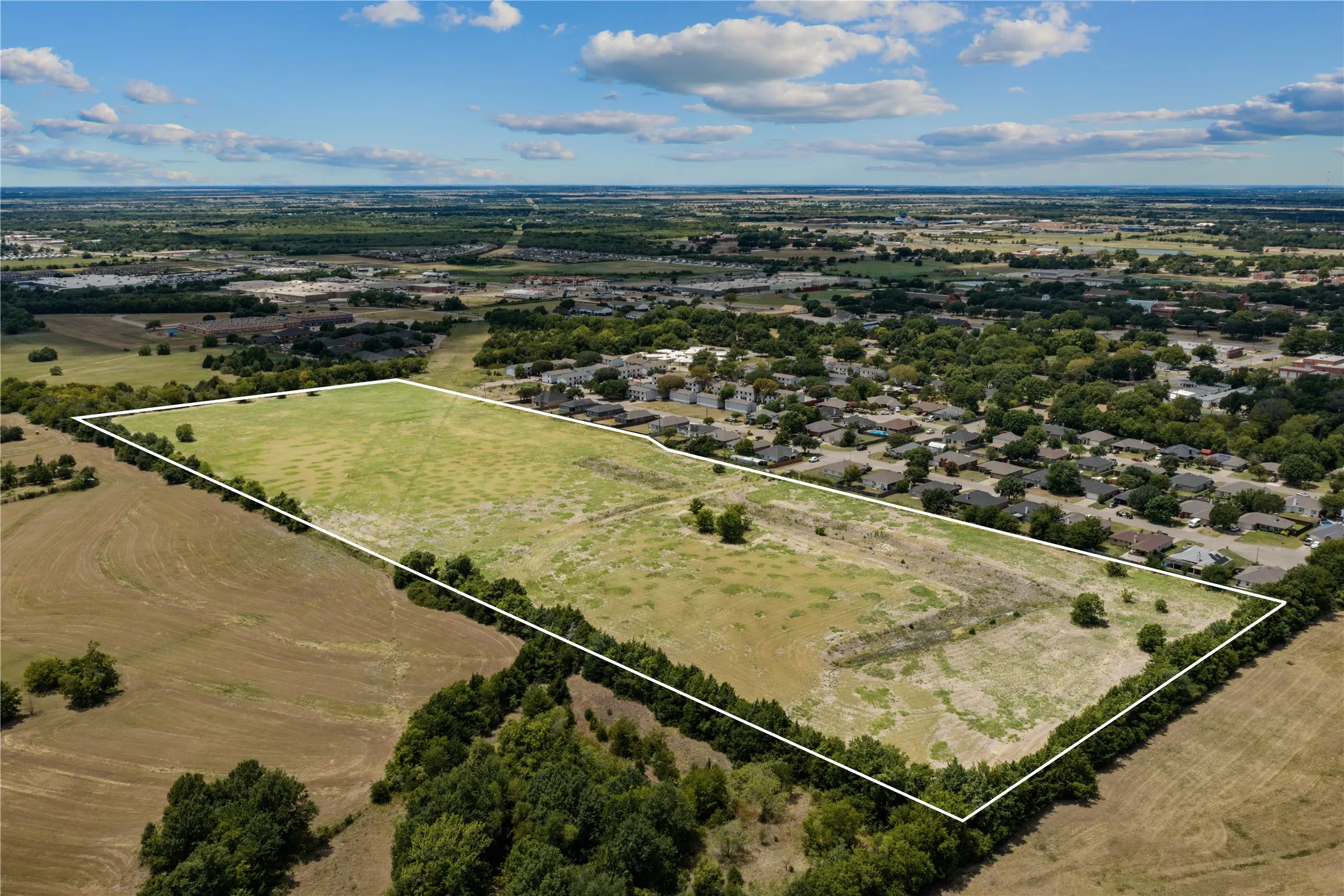 Expansive land parcel featuring open fields and perimeter tree lines
