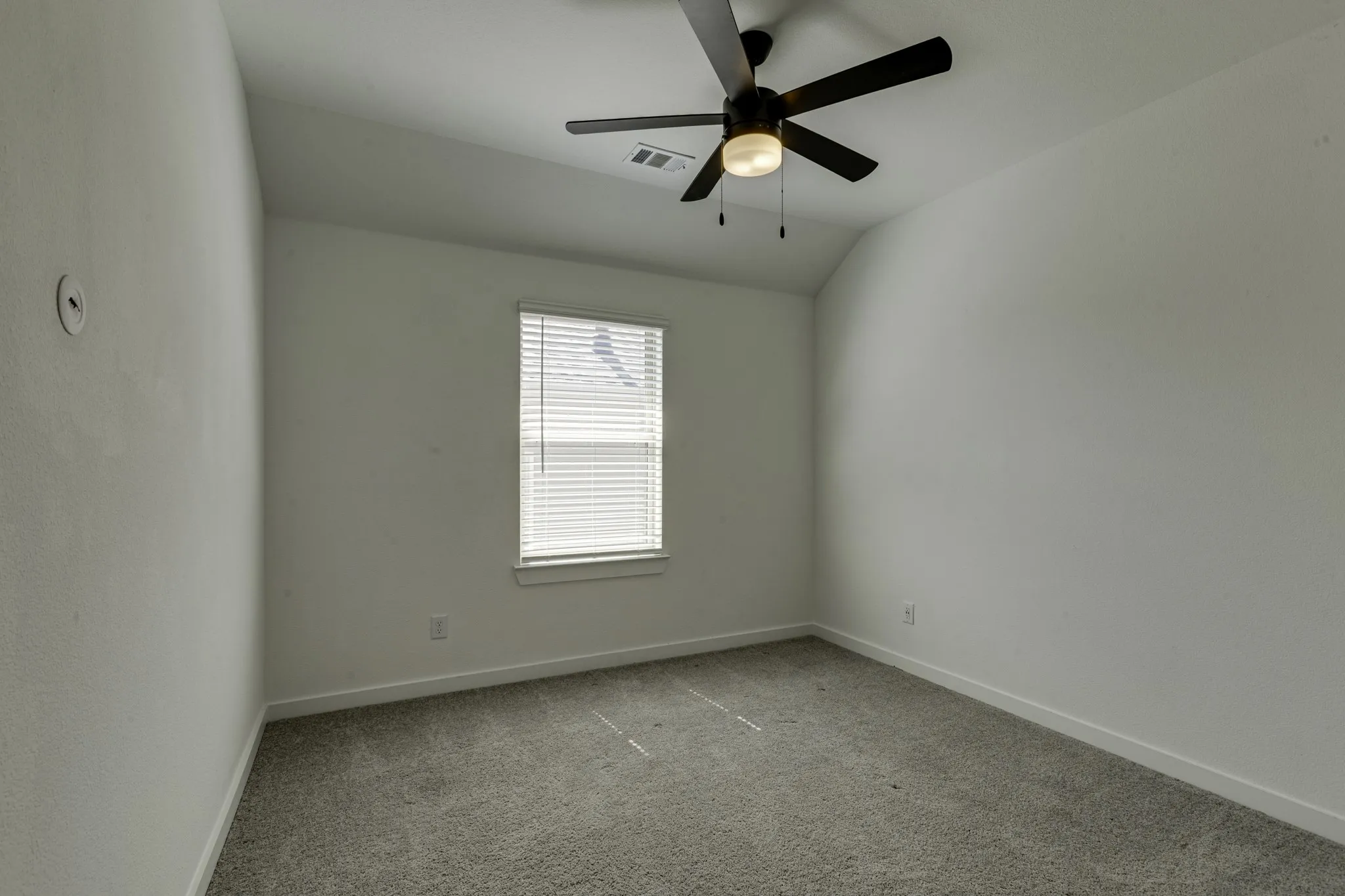 Upstairs bedroom #1, with vaulted ceiling with a ceiling fan light fixture, window with blinds, and neutral carpeting