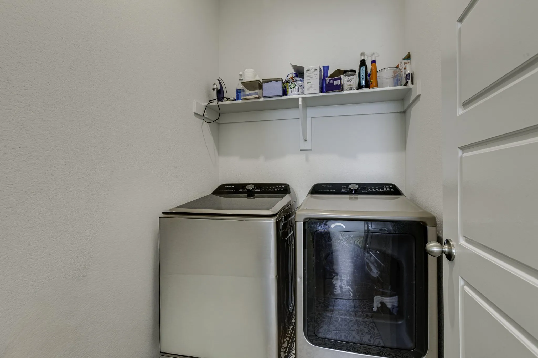 Laundry area with a built-in white shelf and white paneled door