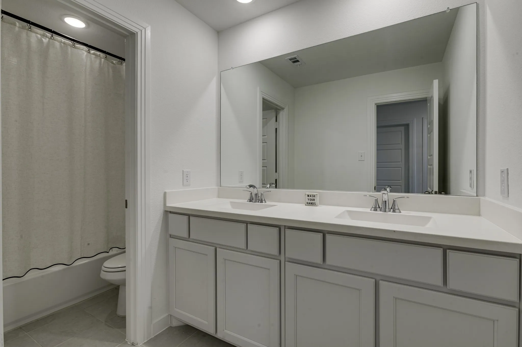 Upstairs bath room with double vanity with undermount sinks, chrome faucets, and light-toned countertops