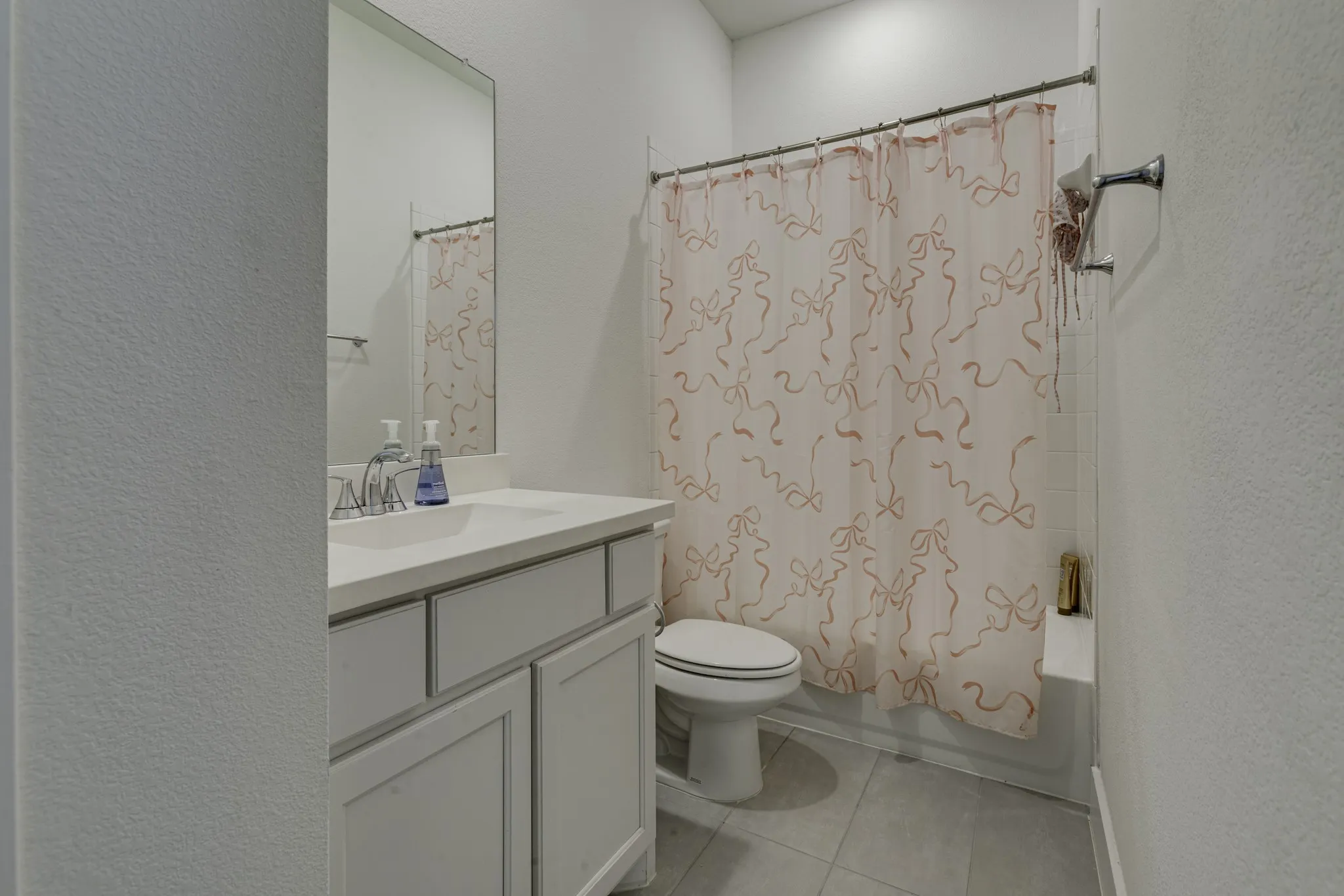 Full bathroom featuring a single vanity with storage, integrated sink, large wall-mounted mirror, and a shower-tub combination