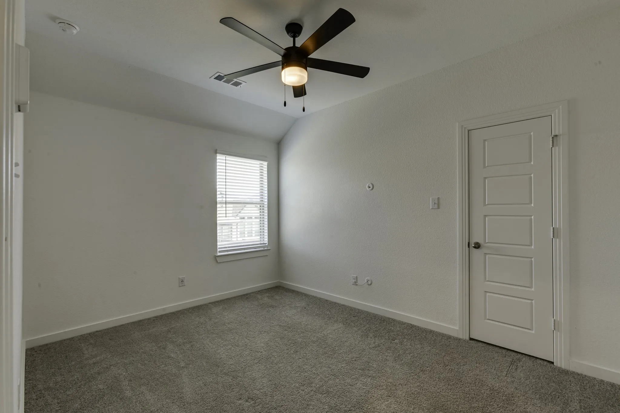 Upstairs bedroom #2 with neutral wall paint, gray carpeting, single window with blinds, modern ceiling fan with light, and a five-panel interior door