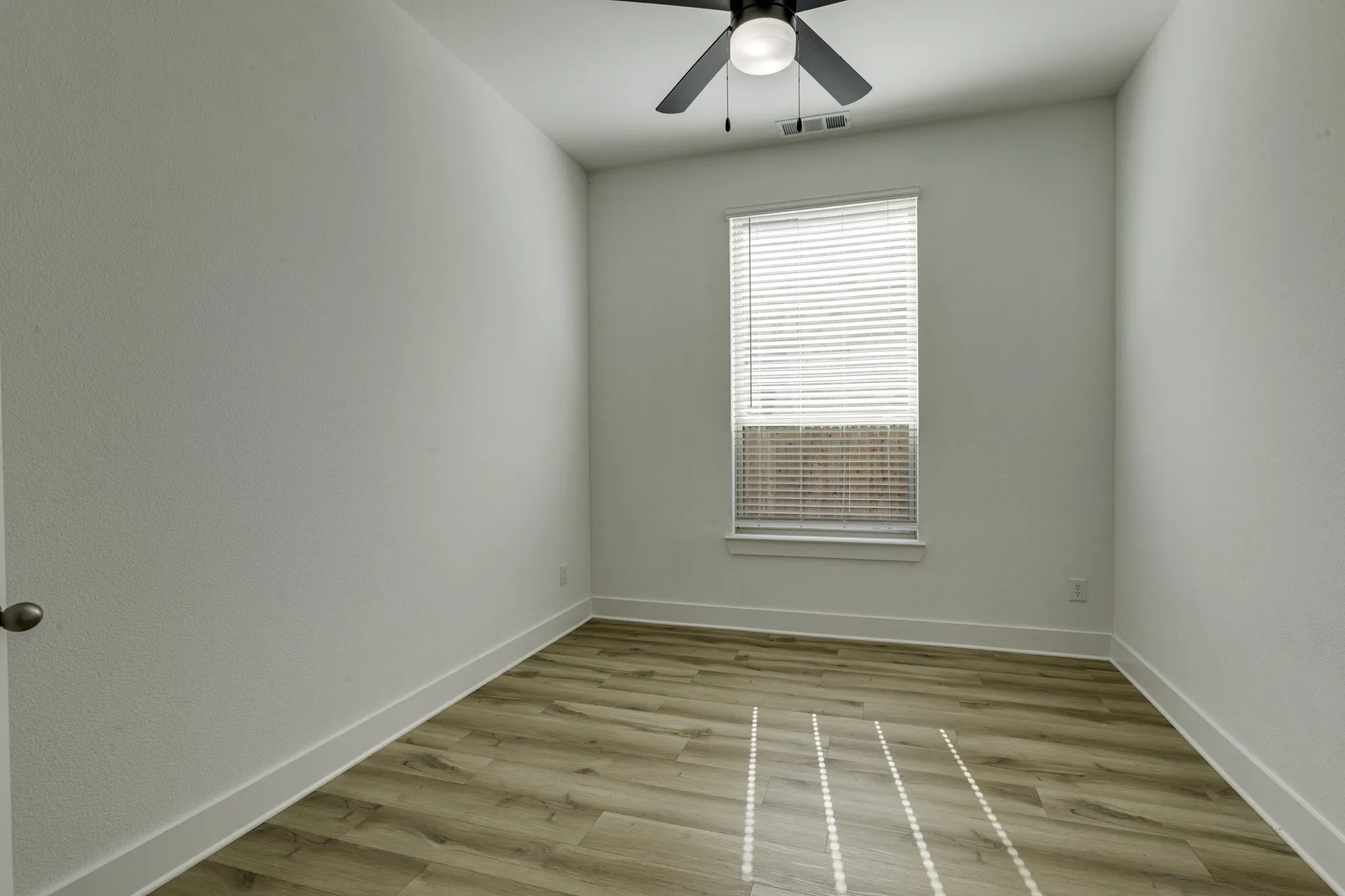 Wood-finish flooring, ceiling fan with integrated lighting, and a window with blinds