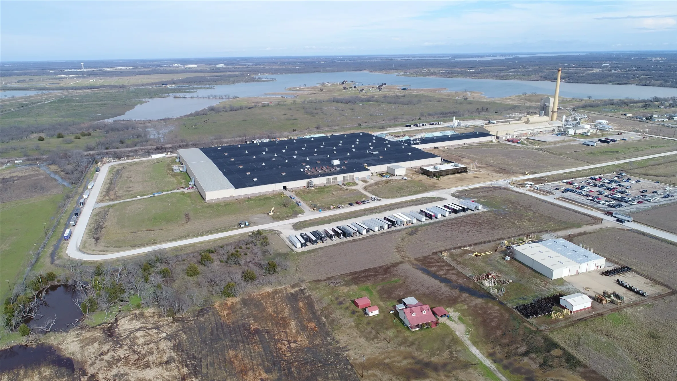 Large industrial building with expansive paved lot and adjacent structures