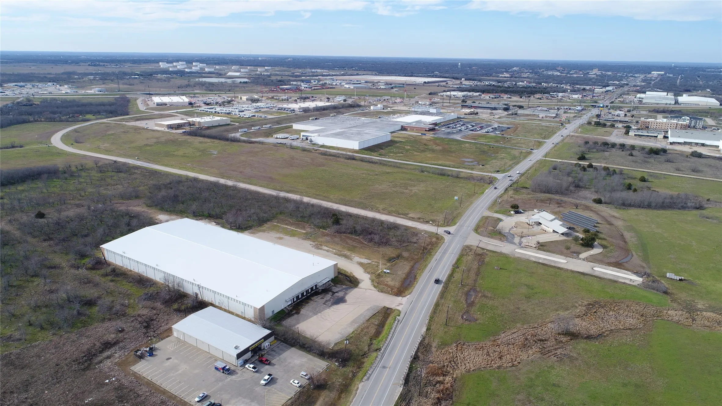 Expansive commercial lot featuring a large warehouse structure, a smaller ancillary building, and paved roadway access