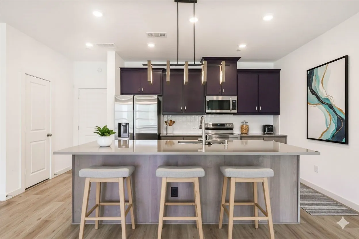 Kitchen with appliances with stainless steel finishes, an island with sink, a breakfast bar, tasteful backsplash, and light wood-style flooring
