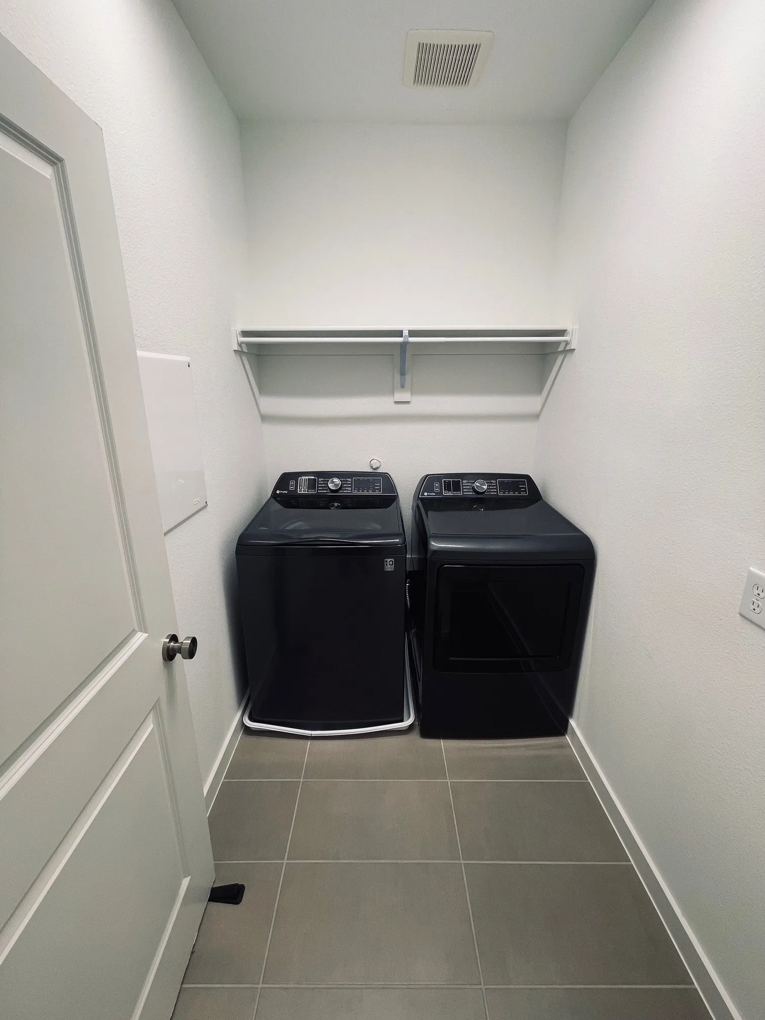 Washroom with light tile patterned floors and washing machine and dryer