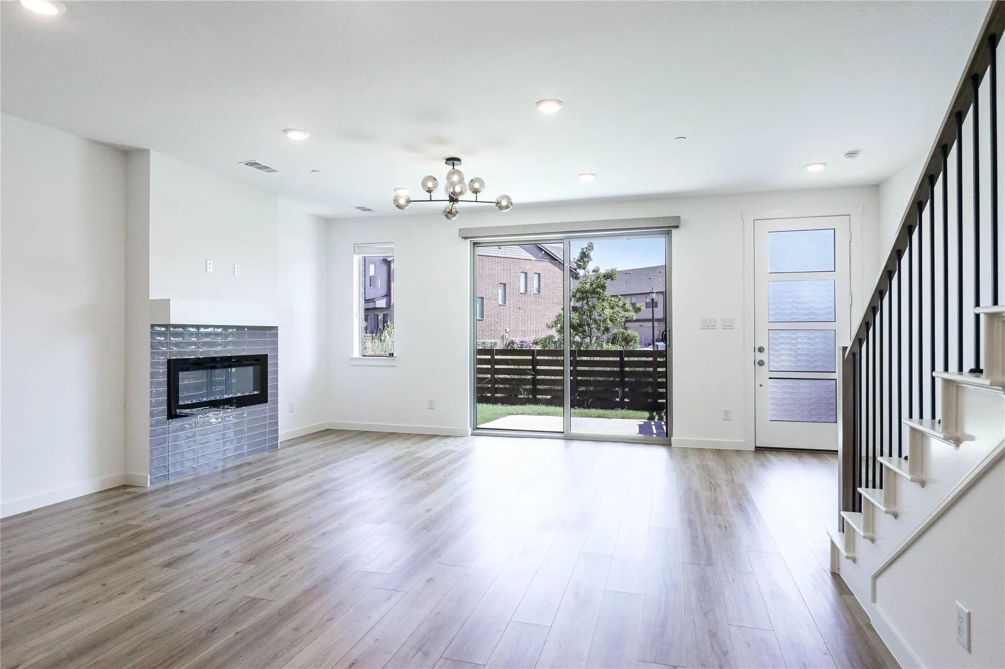 Unfurnished living room with wood finished floors, stairs, recessed lighting, a tile fireplace, and a chandelier